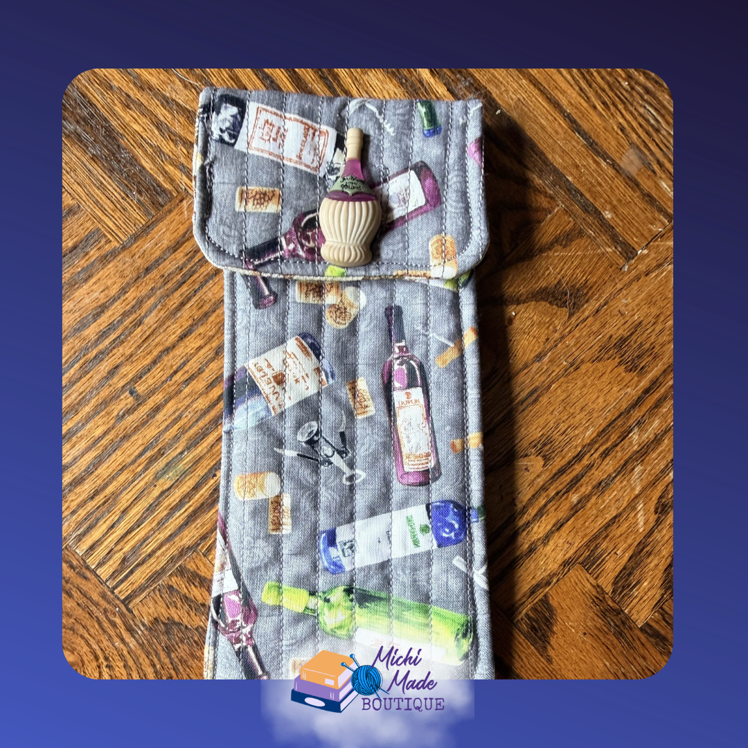 Wine O"Clock. Quilted eyeglass case in grey with illustrated wine bottles, glasses, corkscrews, and labels in purple, pink, and green, with a small wine bottle decorative button.