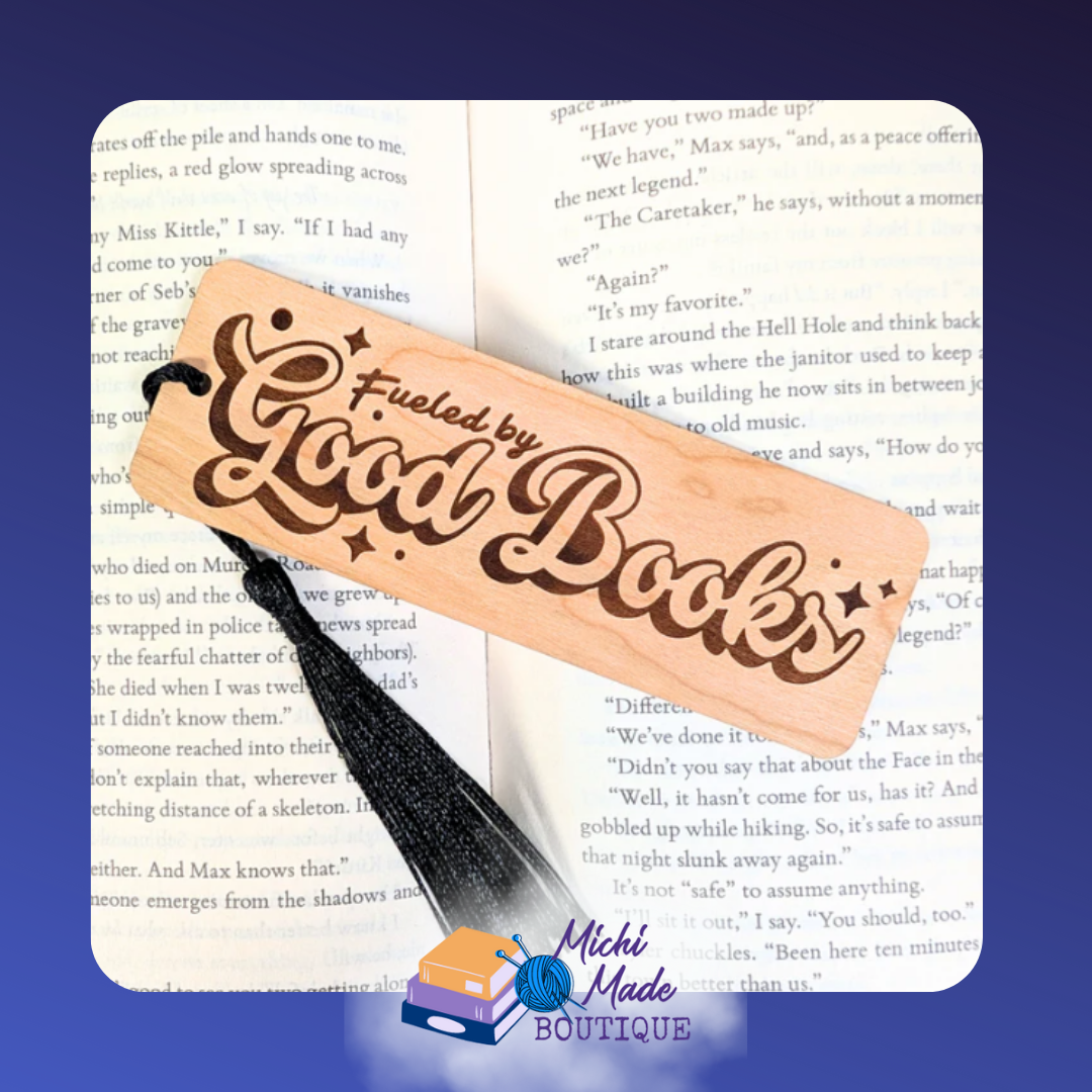 Wooden bookmark engraved with “Fueled by Good Books” in bold script, black tassel attached.