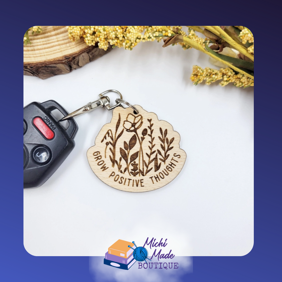 Wood keychain with “Grow Positive Thoughts” encircling etched wildflowers.