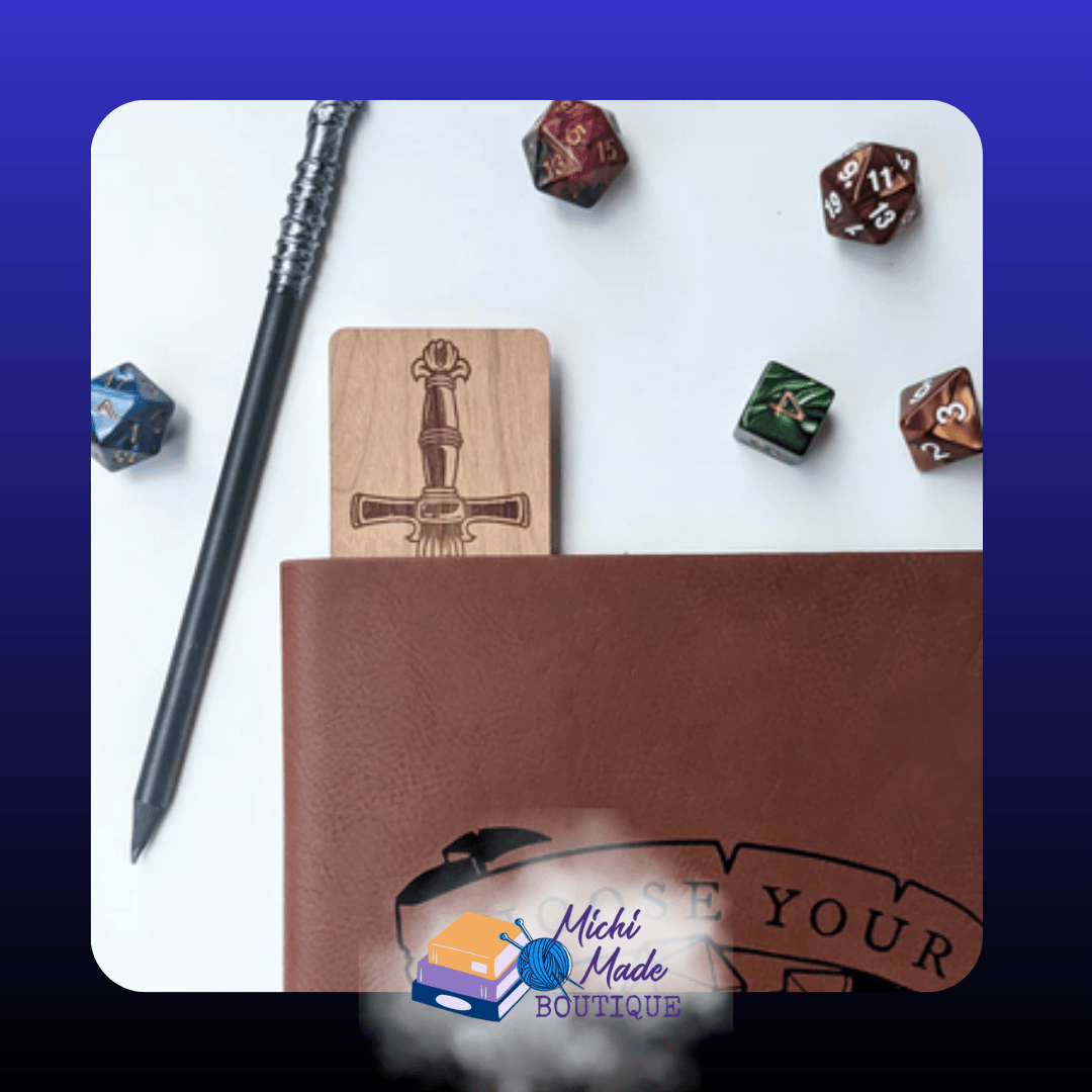 Dice Sword in Book: “Engraved wood bookmark peeking from a brown journal, showing the sword hilt design, surrounded by polyhedral dice and a wand.”