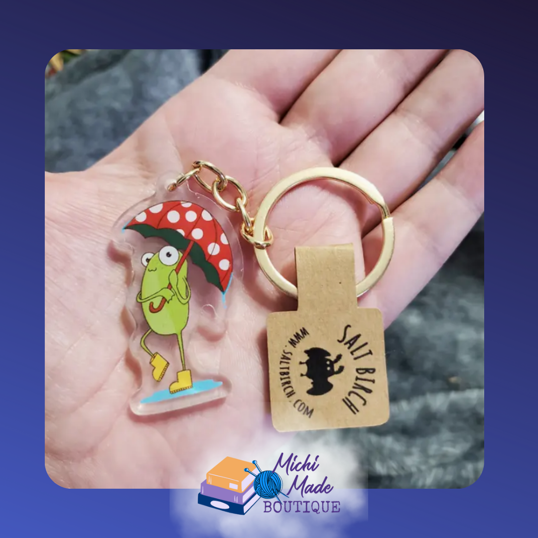 Frog keychain holding red polka-dot umbrella in rain boots.