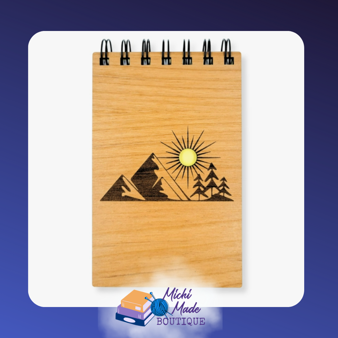 Small wood-cover notepad engraved with mountains, pine trees, and sun.