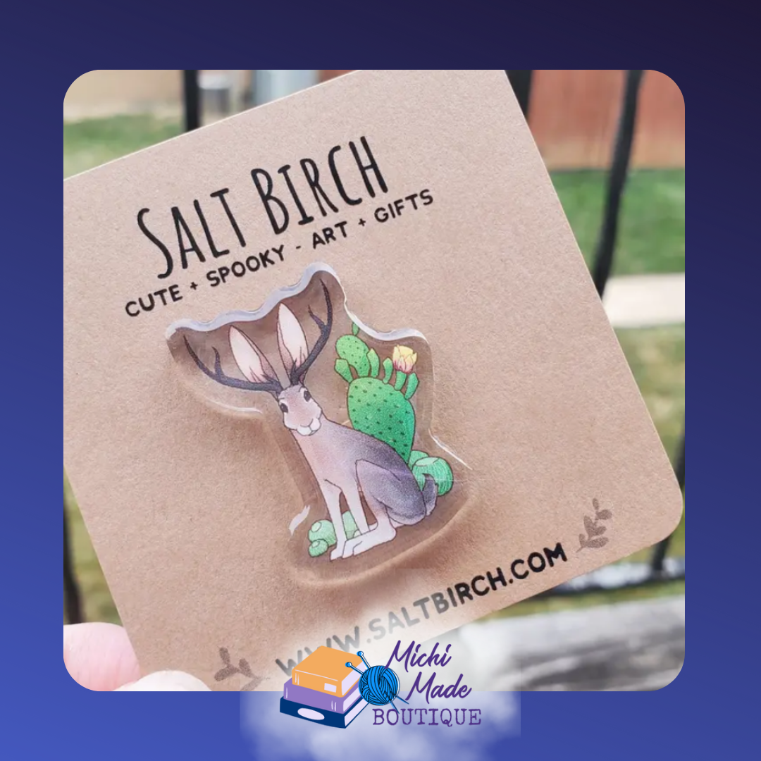 Acrylic pin of a jackalope with cactus and flowers.