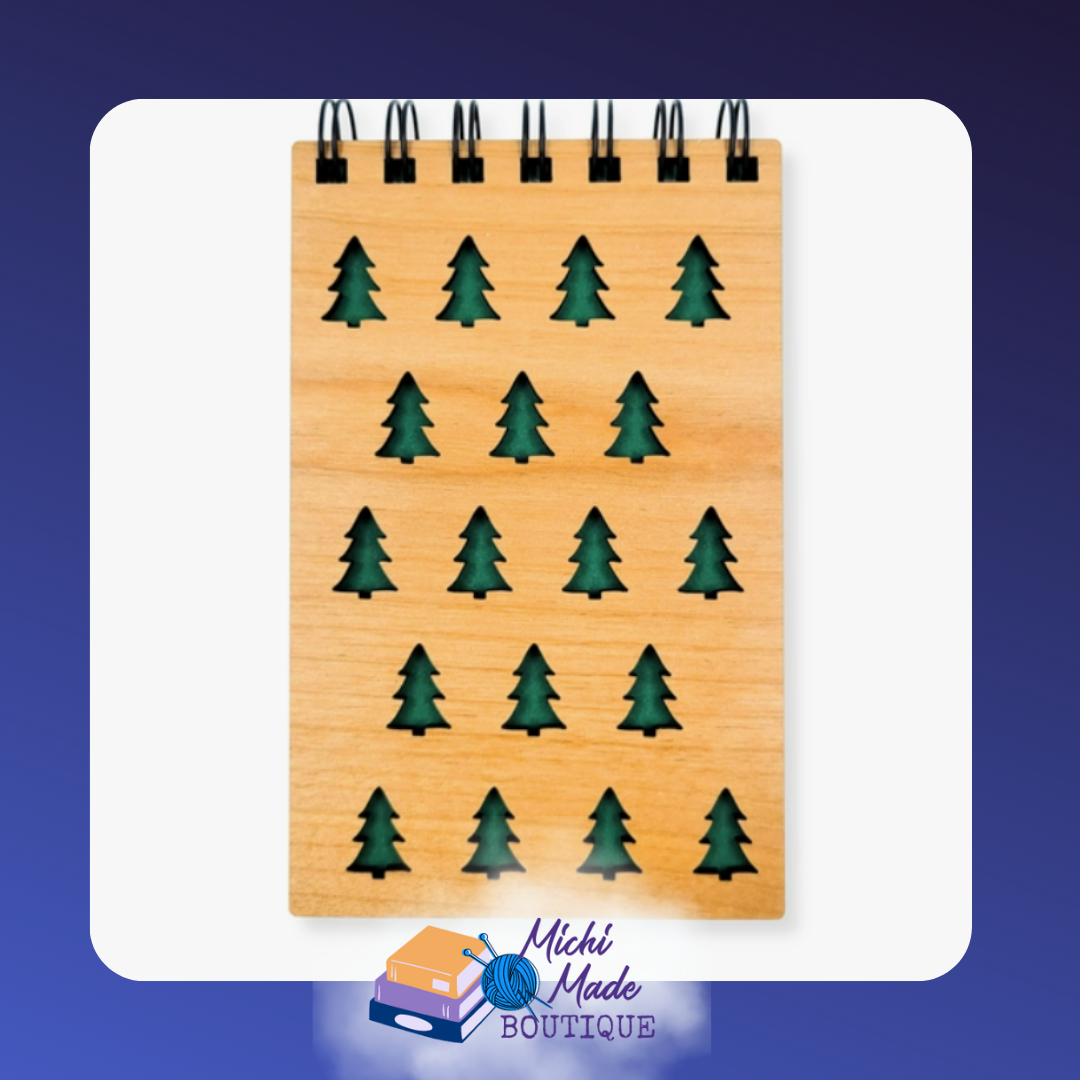 Small wood-cover notepad with repeating green evergreen tree cutouts.