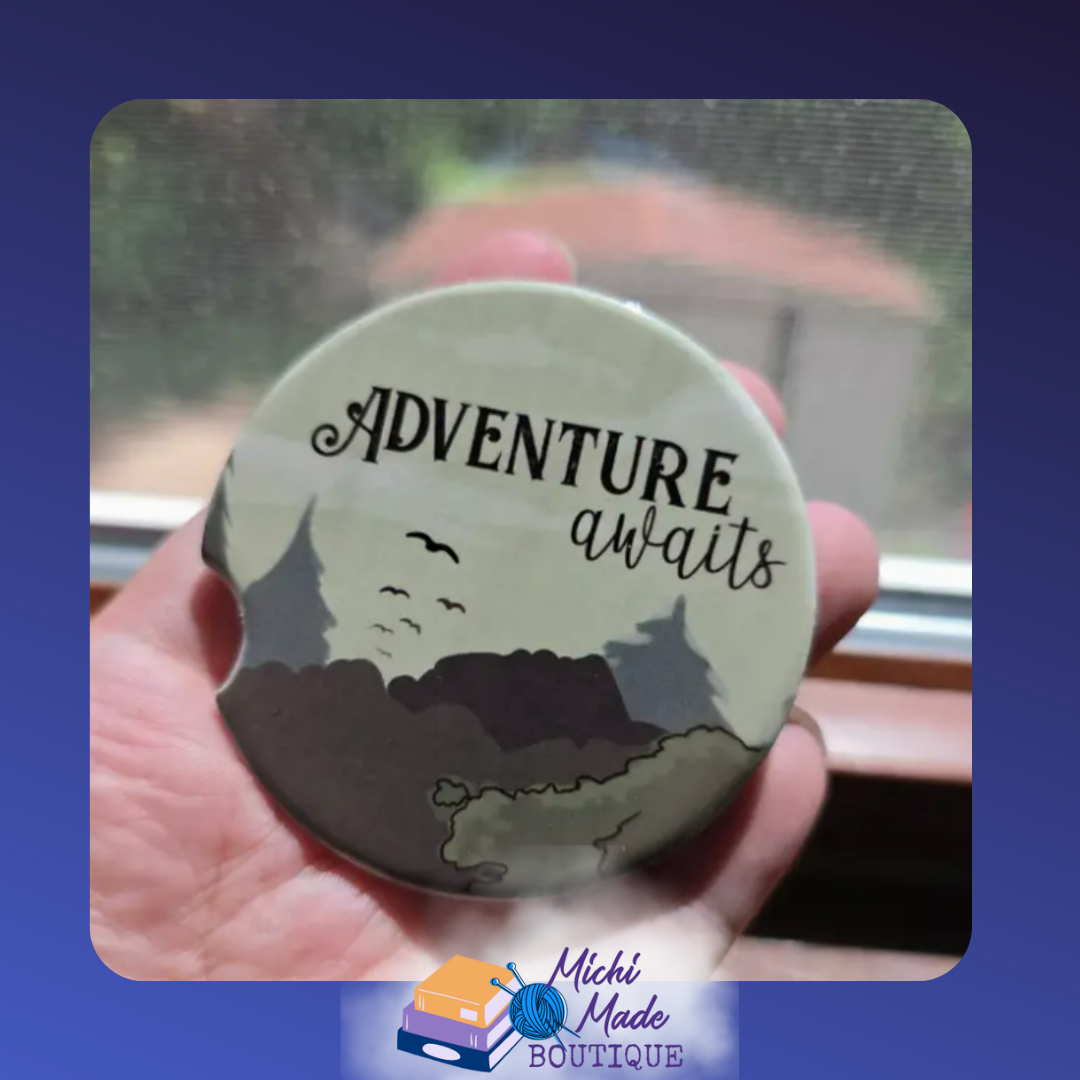 Ceramic car coaster with green forest silhouette and text “Adventure Awaits.”
