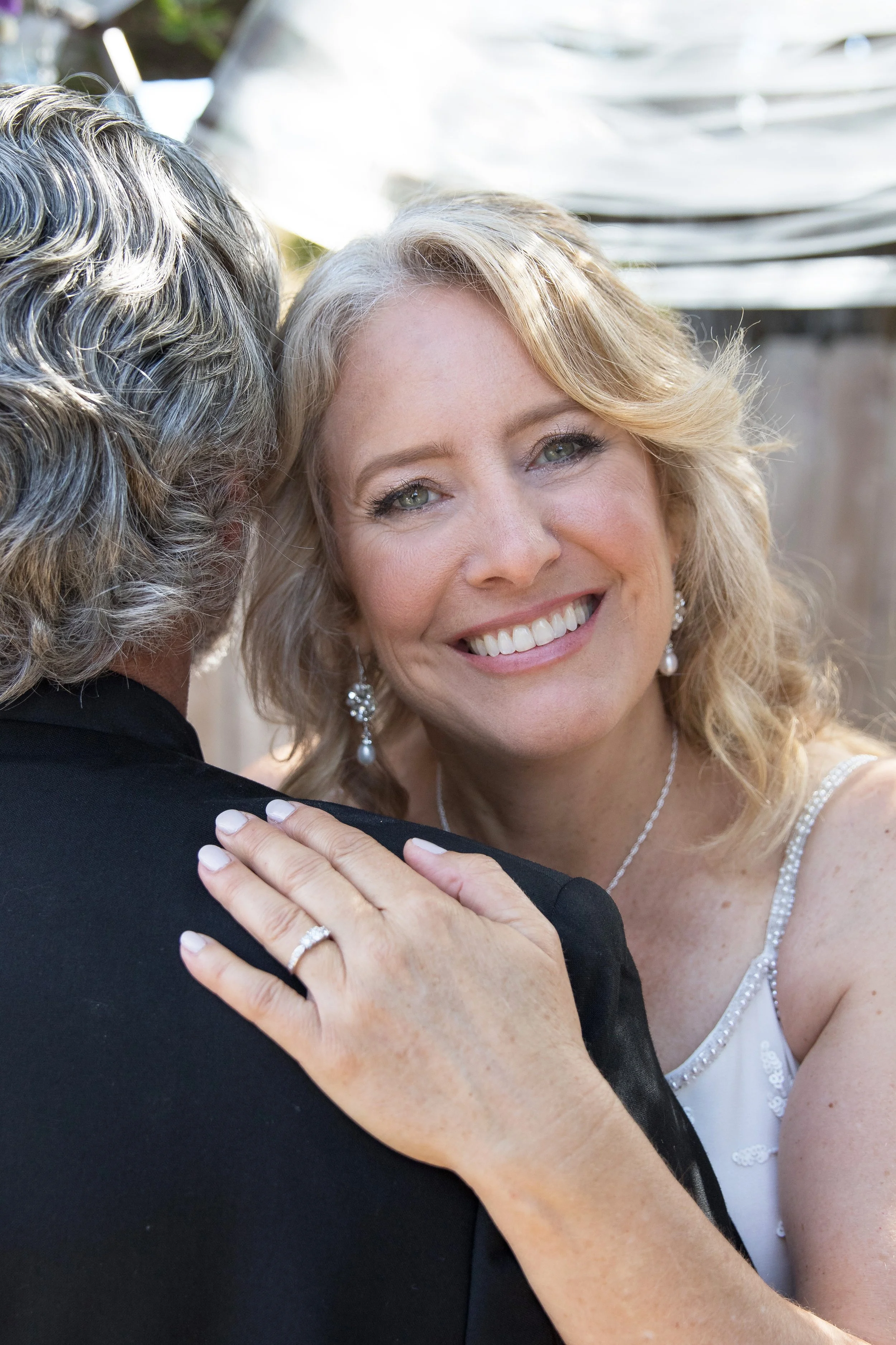 silver bride smiling over the groom's shoulder, older couple, on their wedding day