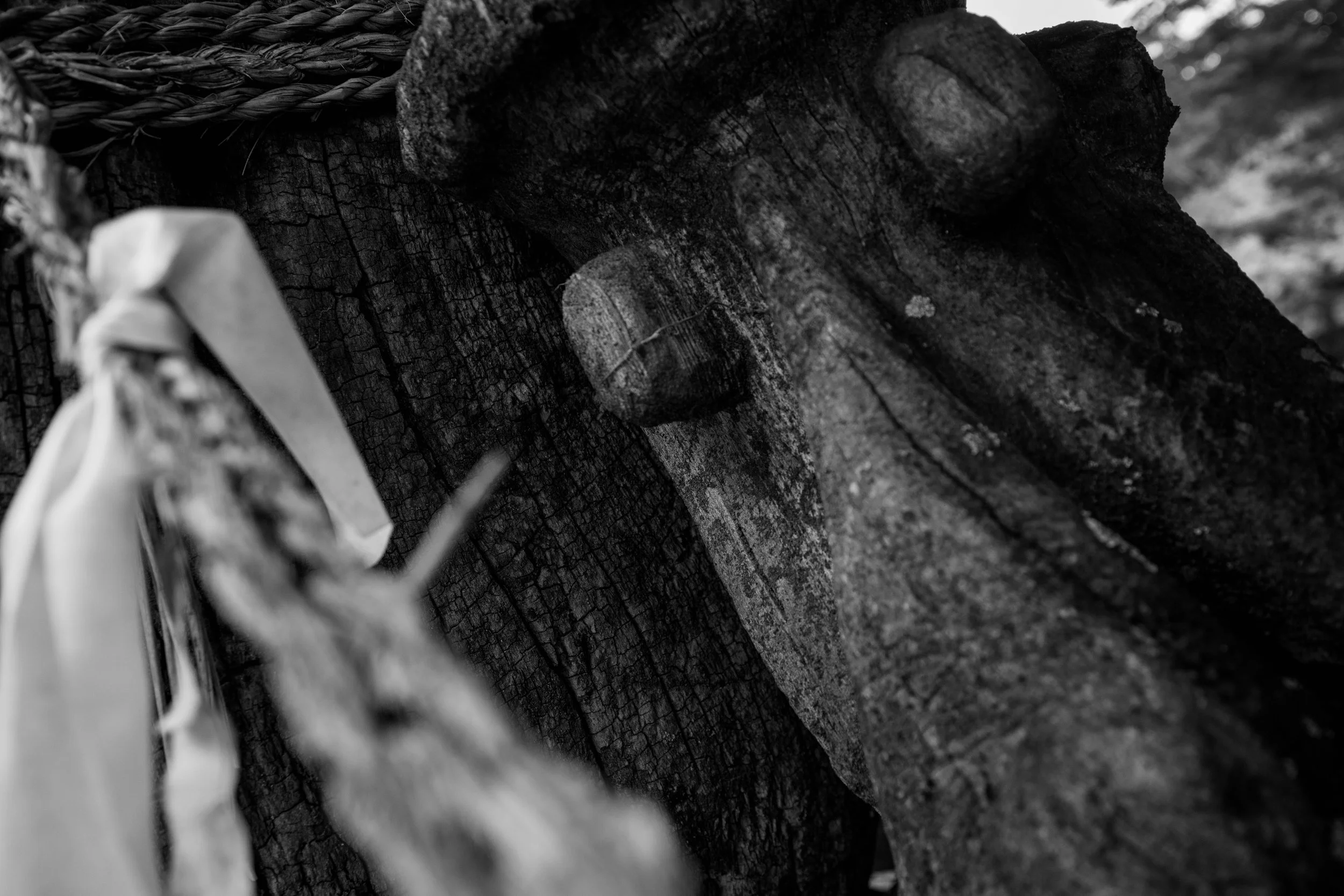 A closeup of a wooden totem with large, carved eyes and a spiritual boundary rope (Geumjul - 금줄).