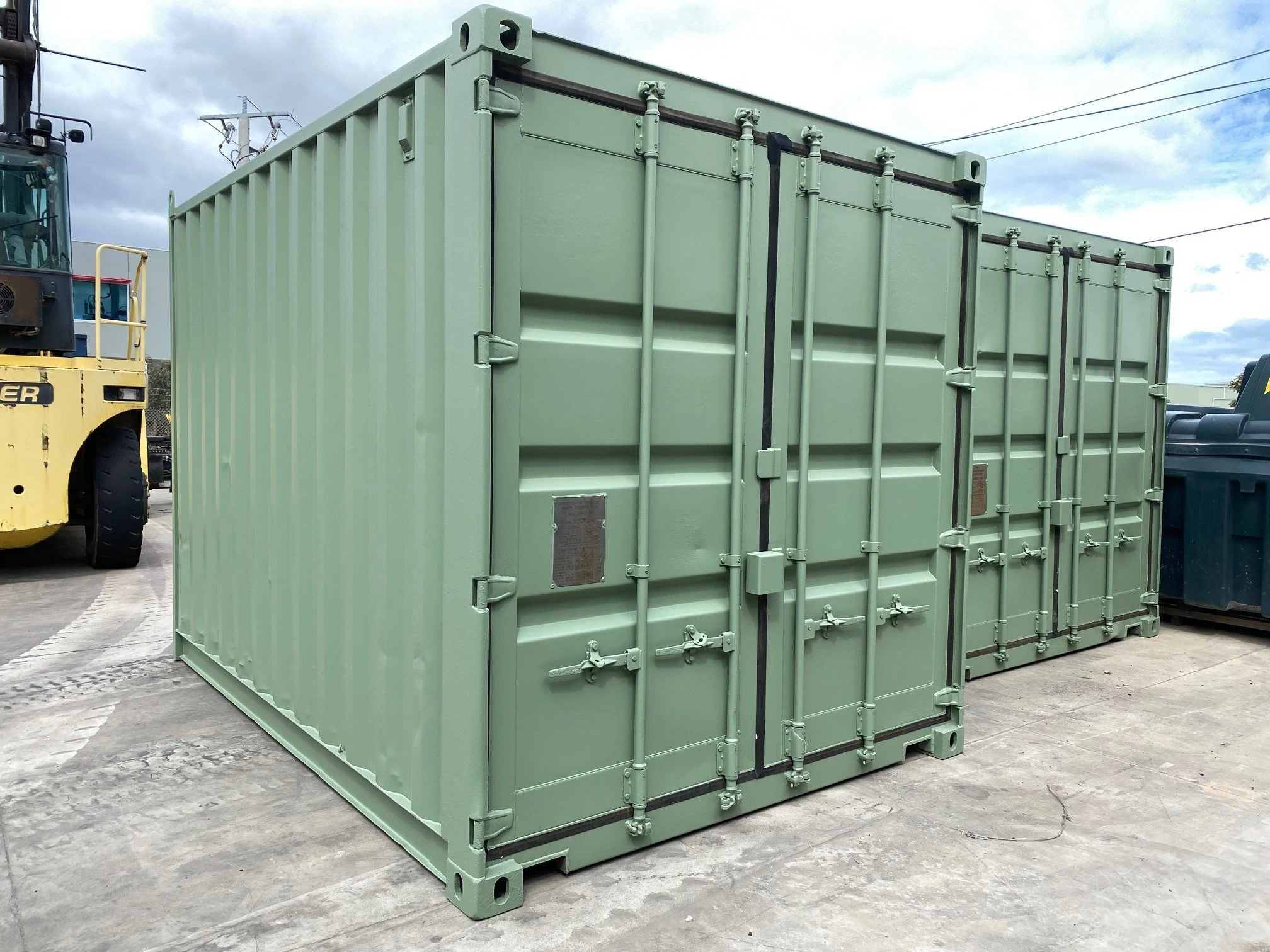 Two shipping containers painted pale eucalyptus green.