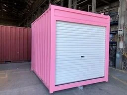 Pink storage container with a white roll-up door in an industrial setting