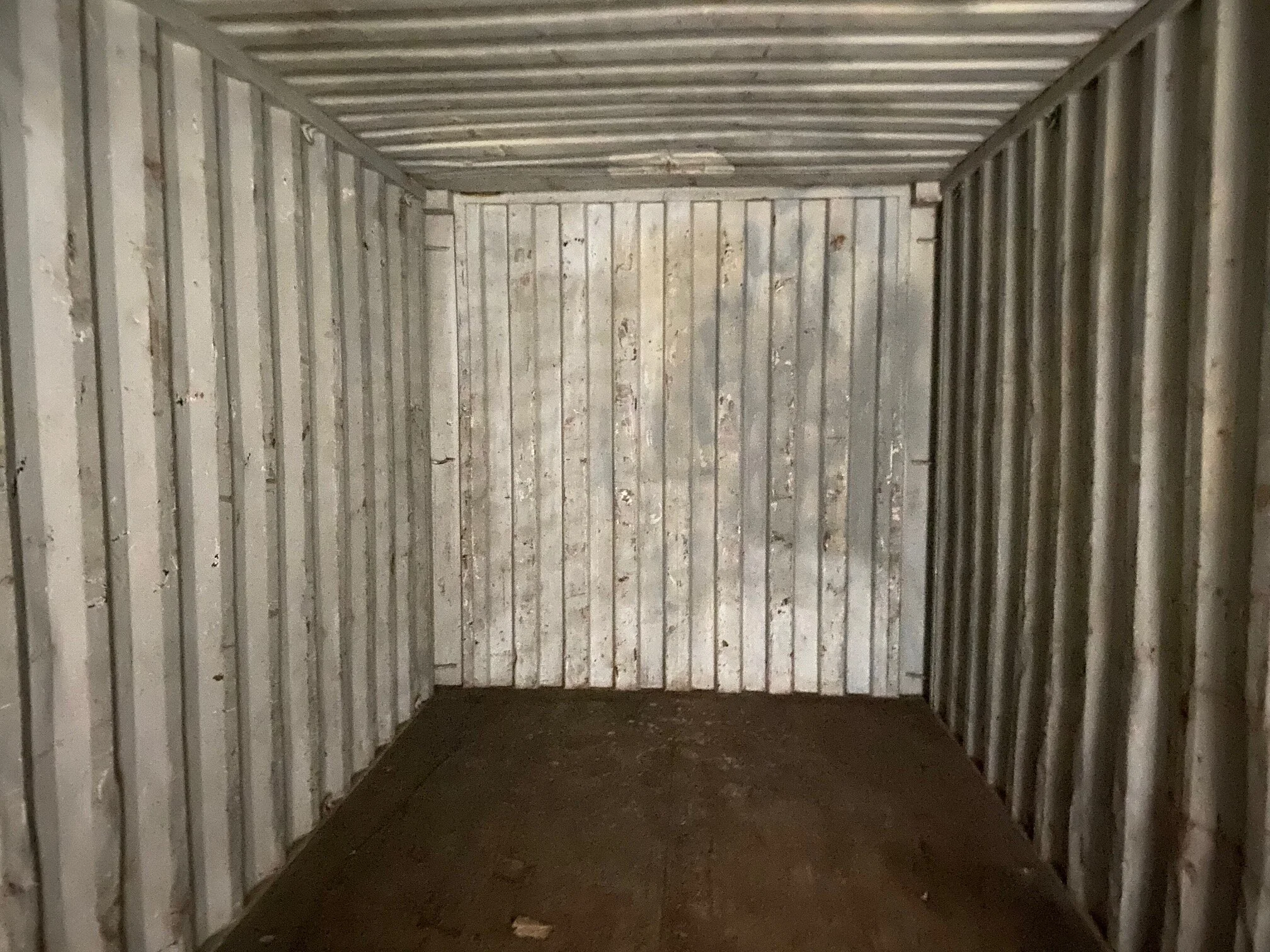 Empty storage unit with metal walls and a concrete floor.
