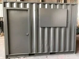 A small shipping container converted with door on the left and a rectangular shutter on the upper right, made of vertically corrugated metal.