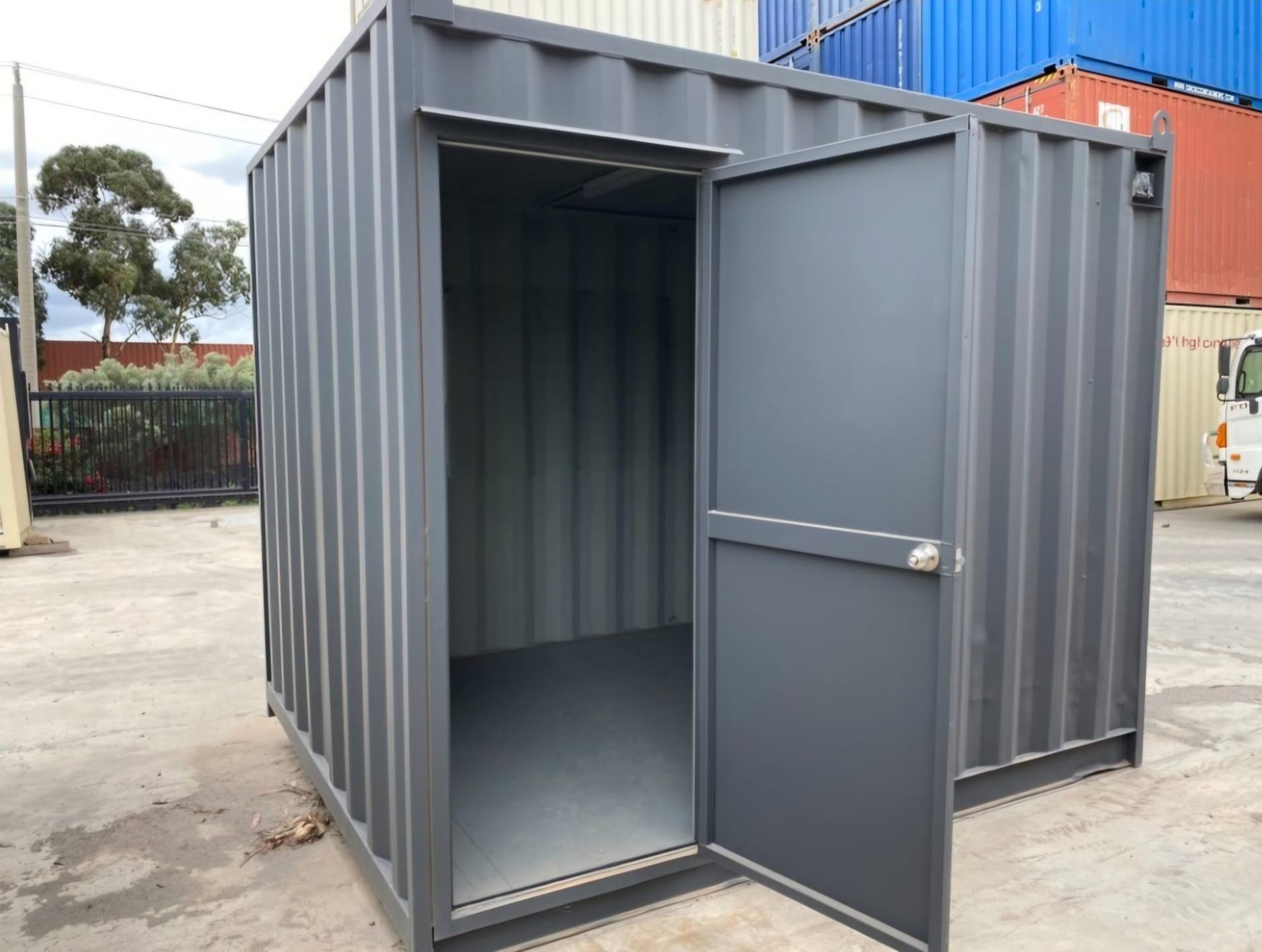 Custom sized grey shipping container with personal access door fitted.  Access door is open.