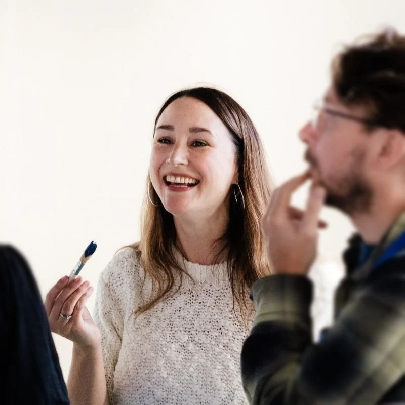 Sam MacKelden, Head of Development, smiling and holding a paintbrush at an ArtHouse Jersey workshop