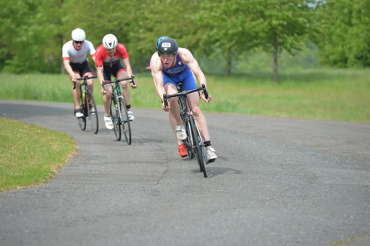 Three cyclists in racing gear ride closely together on a paved road during a competitive event.
