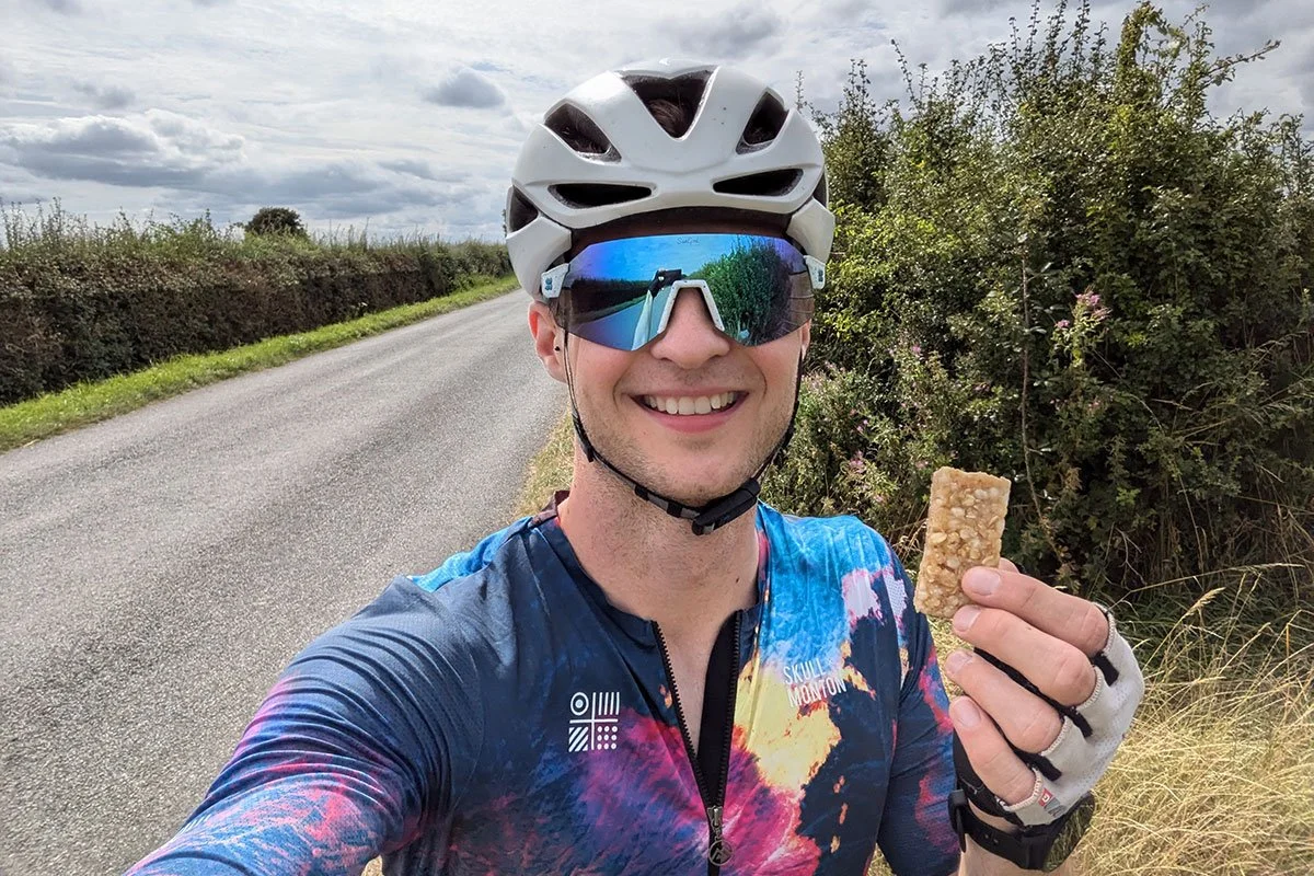 James sitting on a bike and holding a nut bar