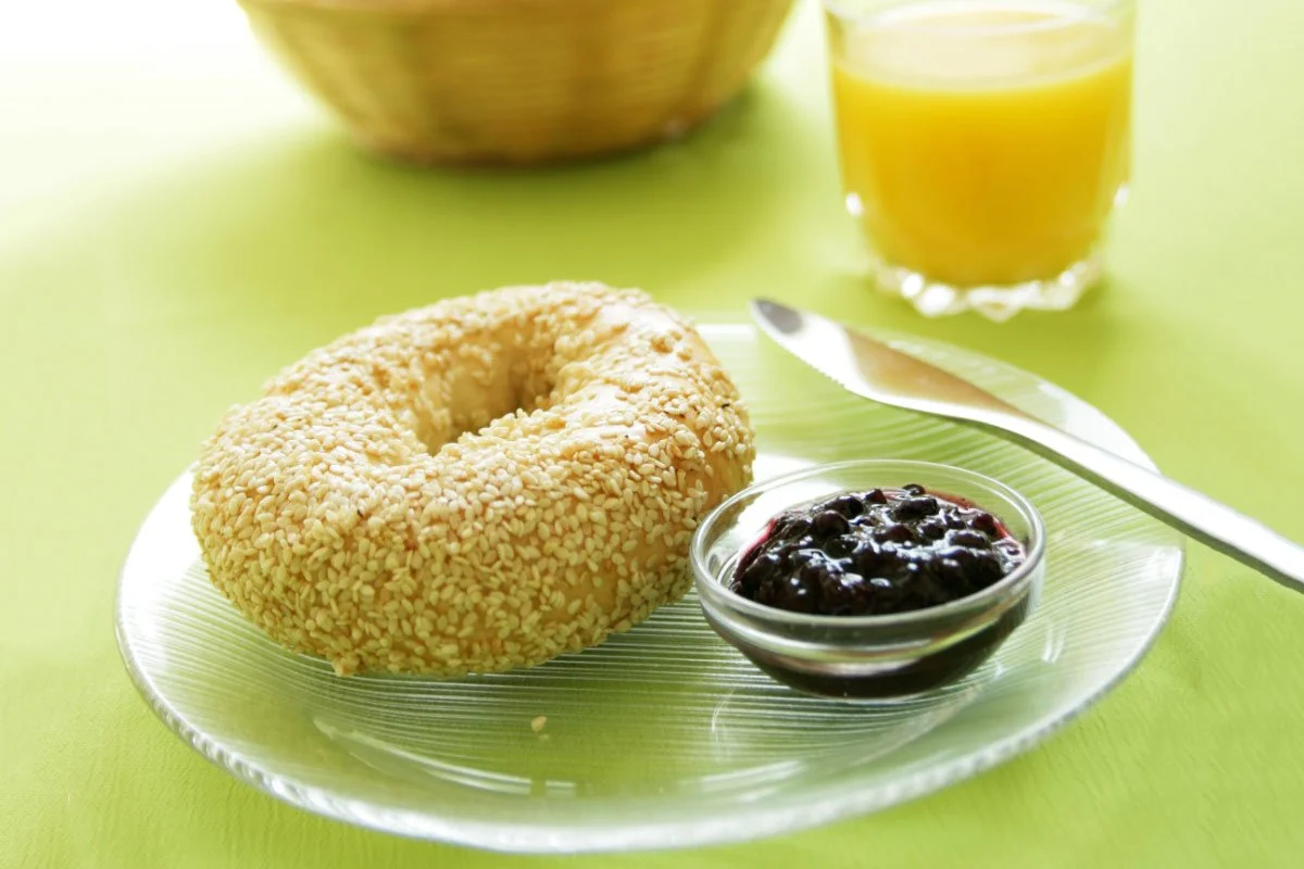 Bagel with jam and a glass of orange juice on a side