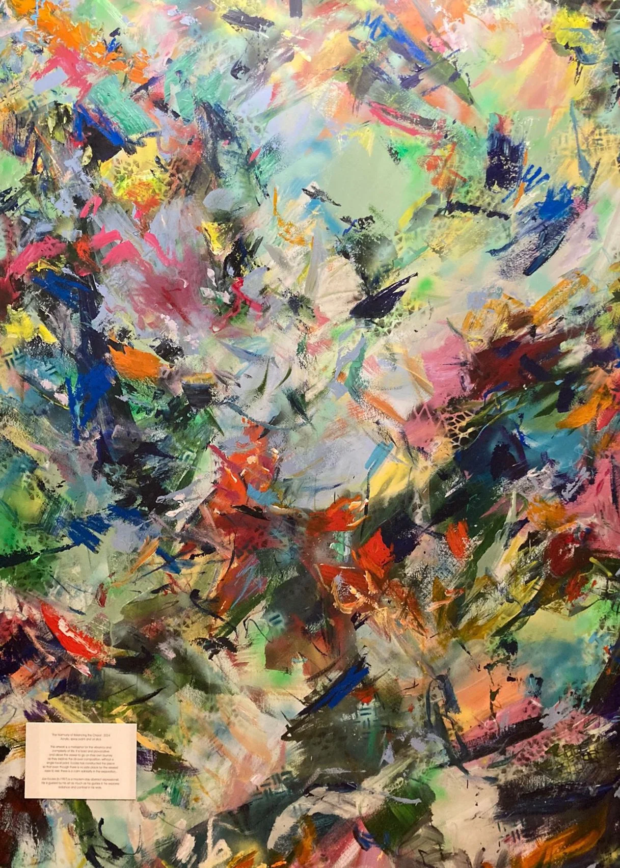 An abstract colorful painting with bold brushstrokes in pink, blue, green, yellow, red, black, and white, creating a vibrant and chaotic composition.