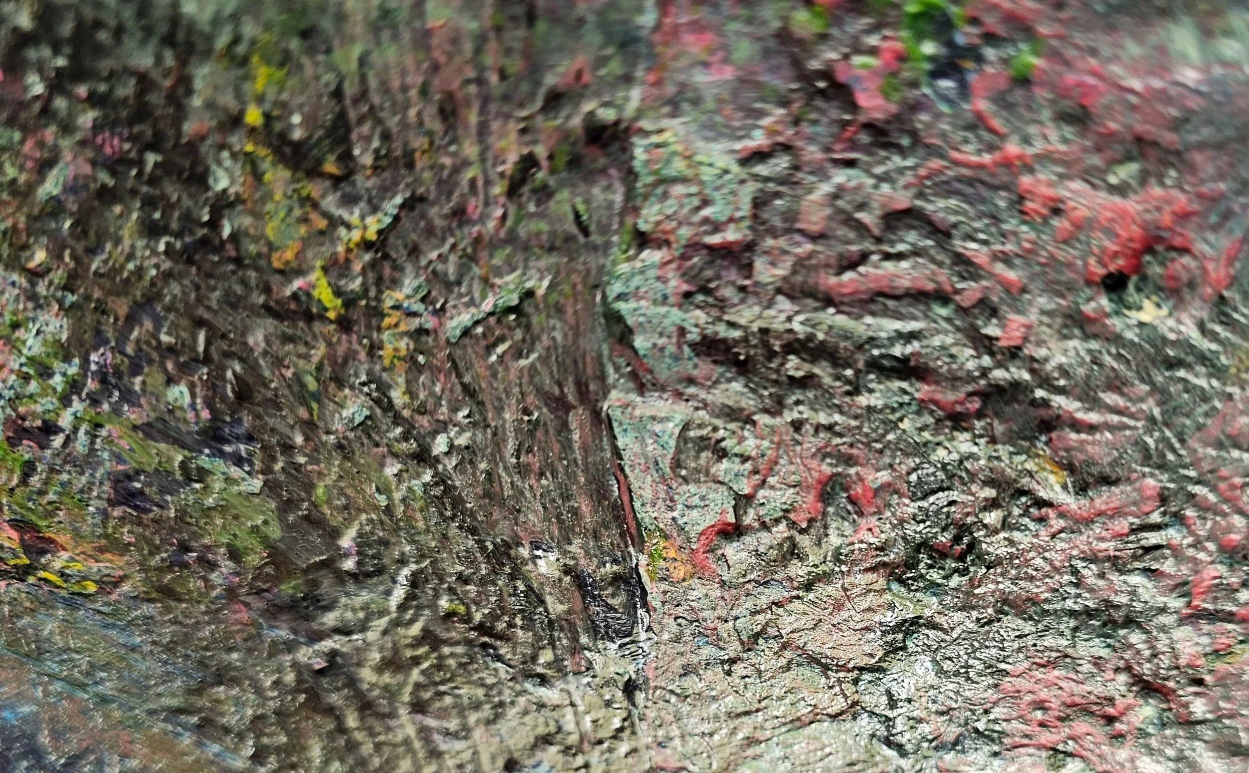 Close-up of a textured, colorful painted surface with thick, uneven layers of paint in green, red, yellow, and black.