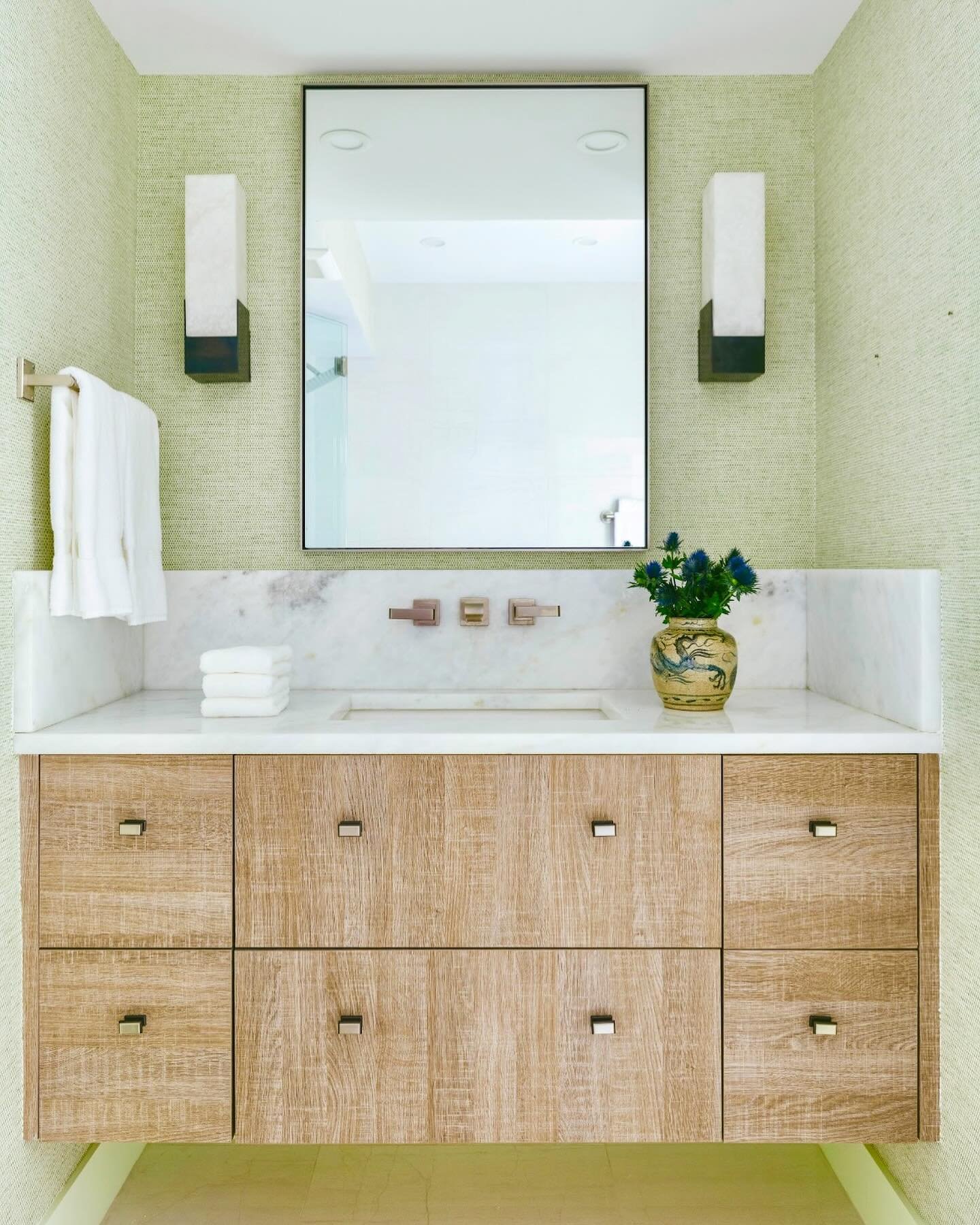A beautiful guest bathroom in a #PalmBeach project, washed in green. @cowtanandtout green grasscloth wallpaper combined with a white oak floating vanity and softened by white marble. 🌿

Styling: @heirlooms.co 
Photography: @nickmelephotography 

#co
