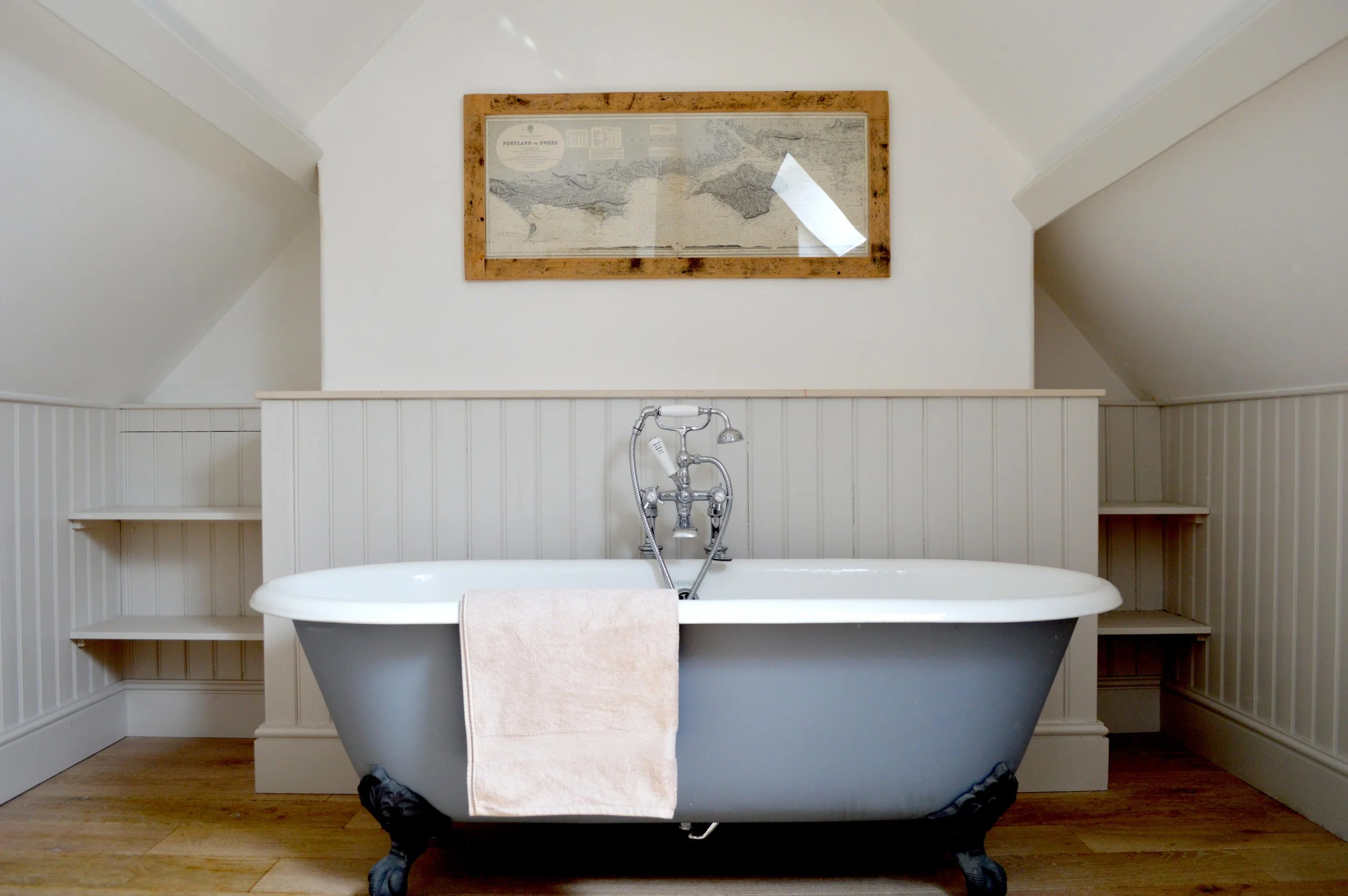 Bathroom at Barton Manor Estate featuring a freestanding roll-top bath, traditional panelled walls and timber flooring.