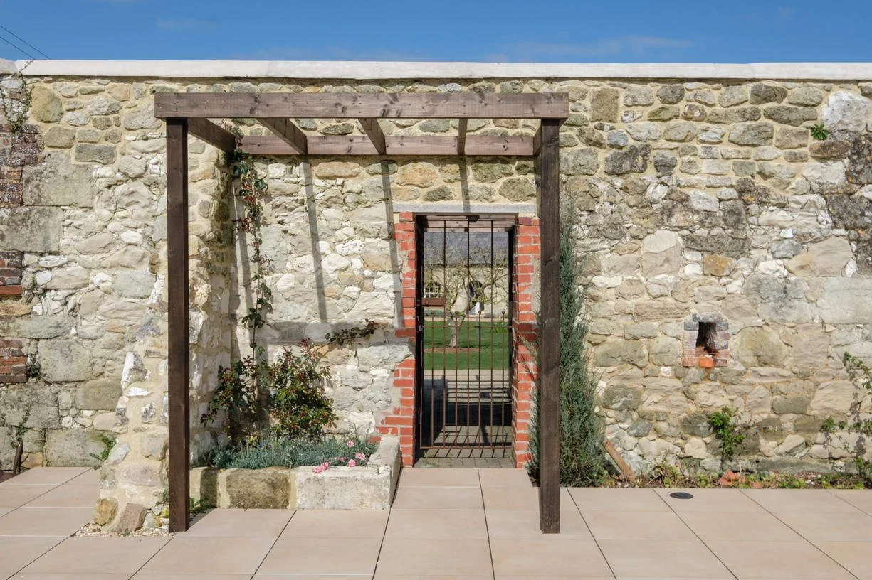 Architectural view of the new pool house at Wacklands Farmhouse, carefully designed alongside the estate's traditional stable buildings to balance contemporary design with historic rural character.