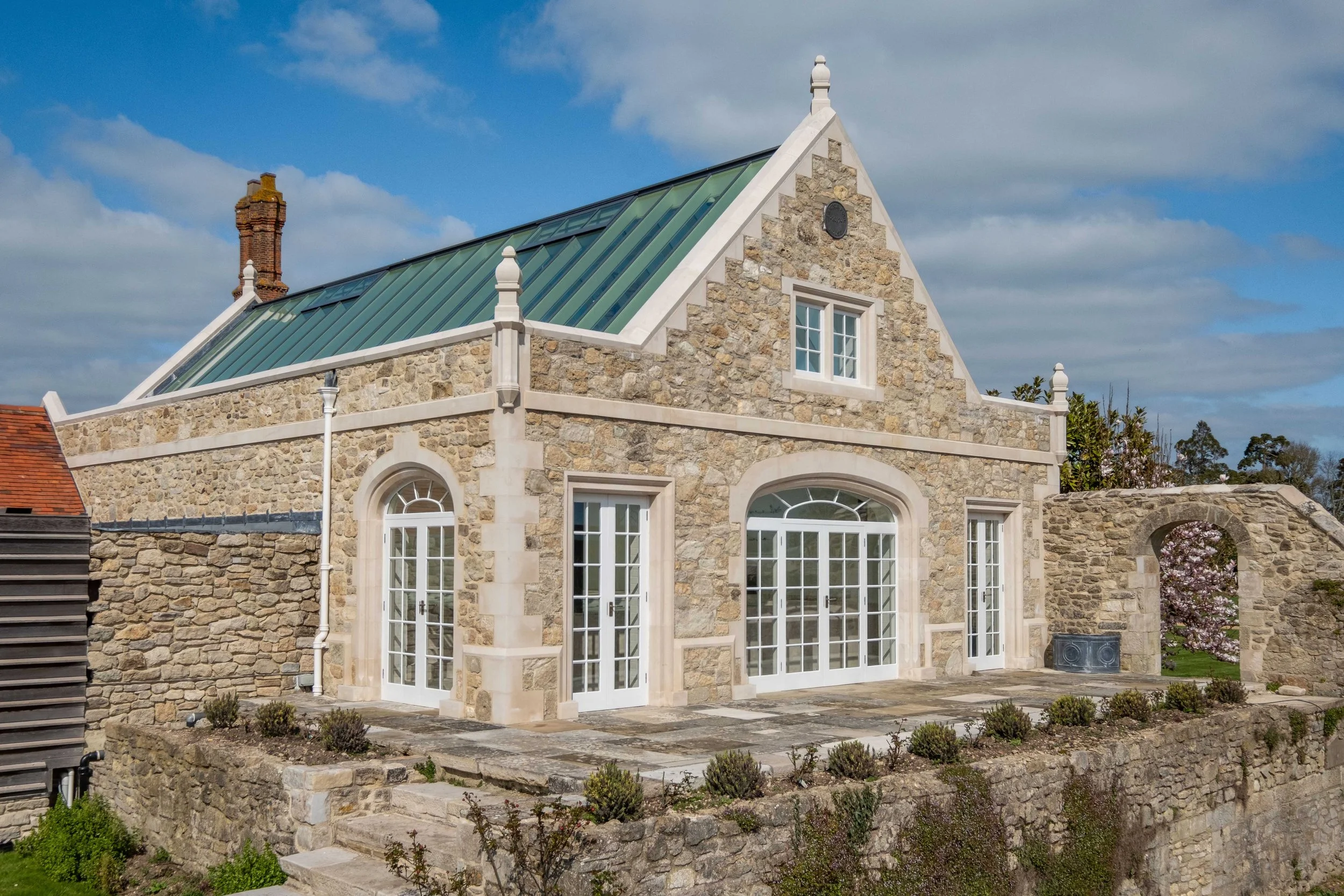 Restored stone building at Barton Manor Estate in Whippingham, with a contemporary metal roof alongside the historic manor buildings.
