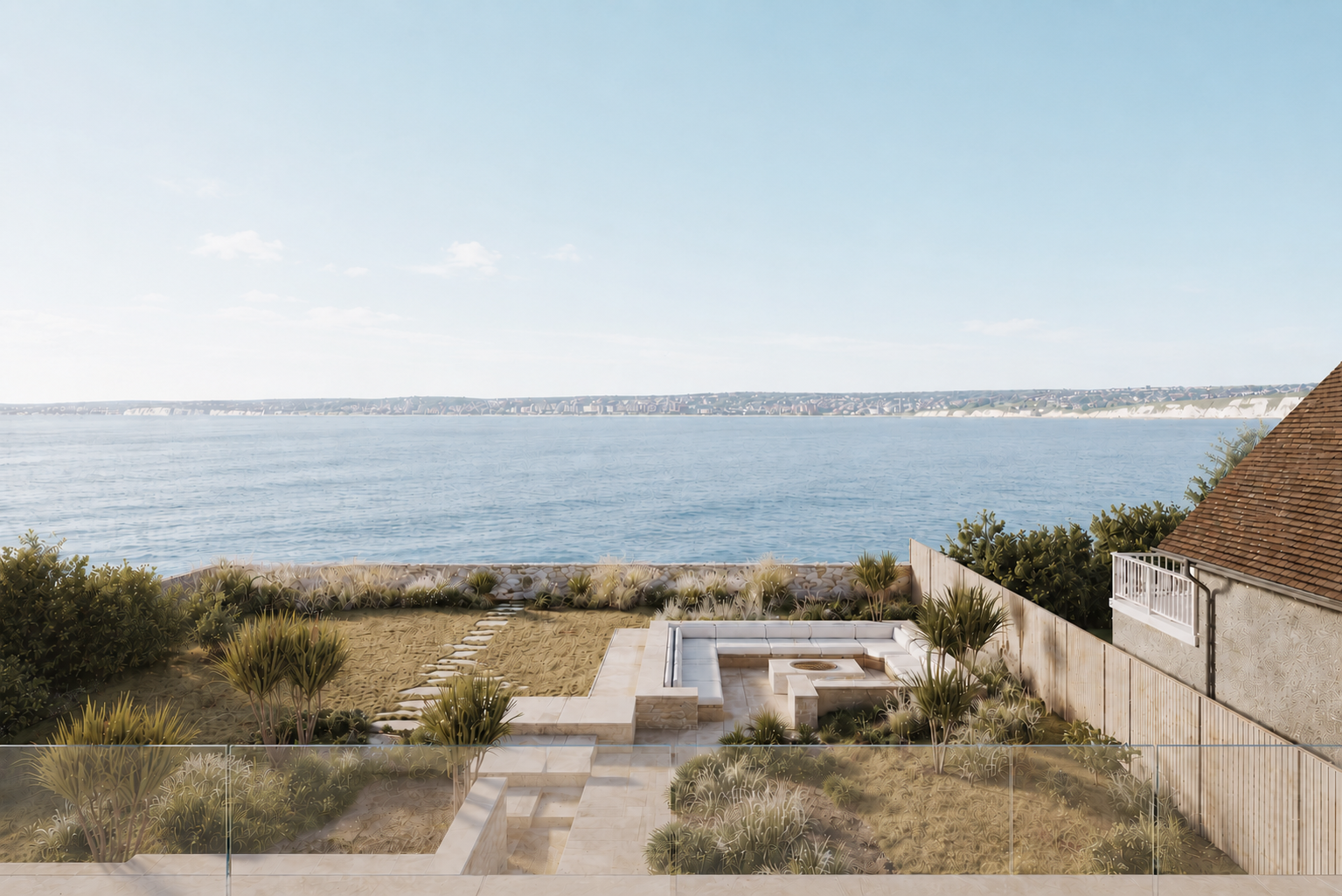 Sheltered outdoor terrace at Fairylee with built-in seating, coastal planting and views across the sea, designed for year-round outdoor living.