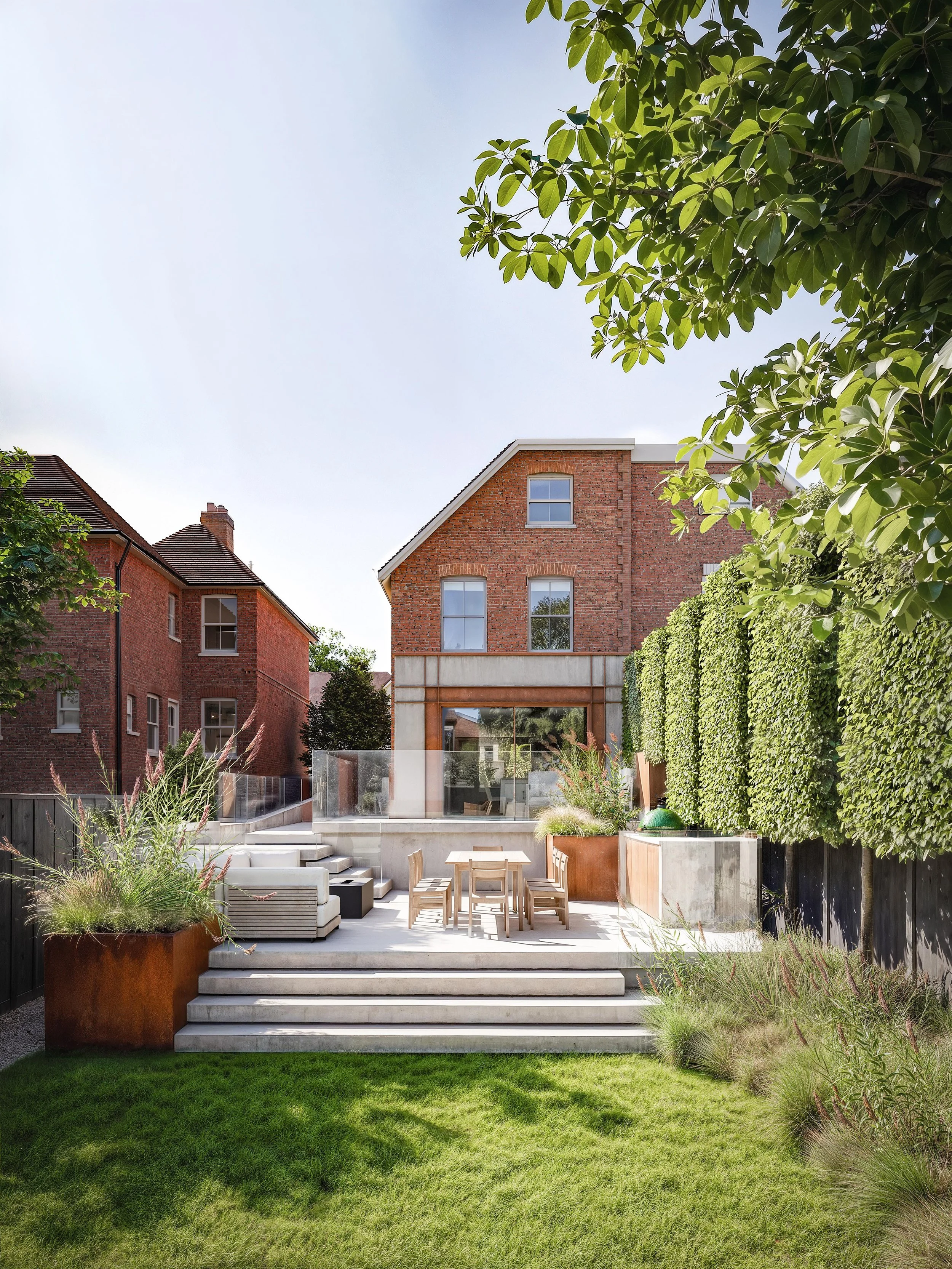 Rear elevation of Donnington House showing the contemporary extension, stepped patio and lawn within the long, sloping garden.