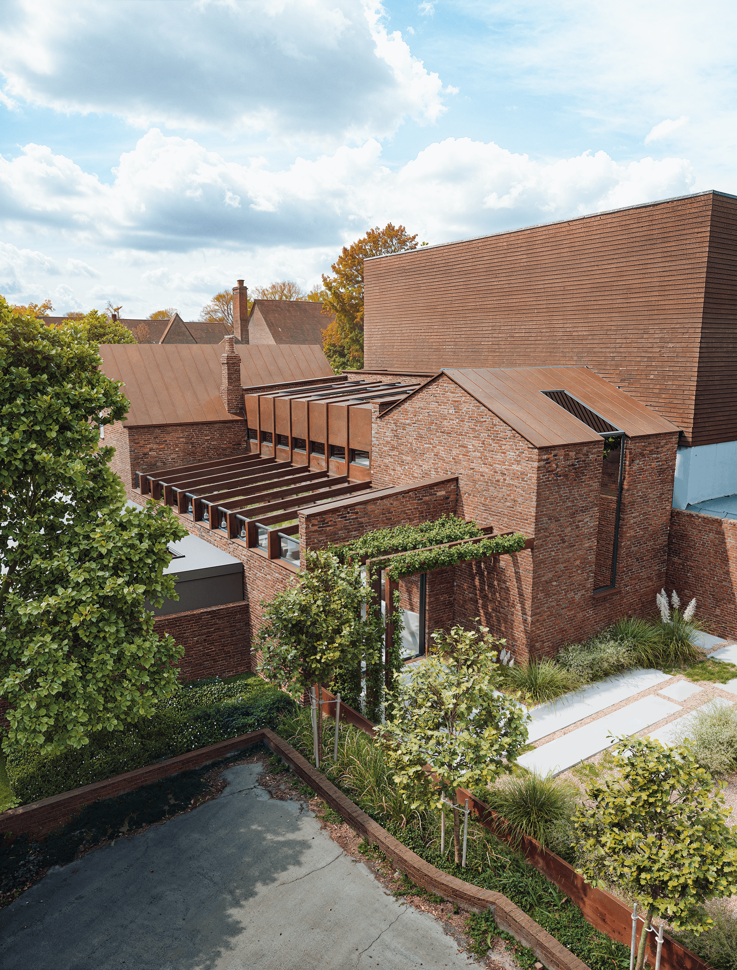 Contemporary Corten steel roof structure spanning the historic brick buildings at The Old Forge in Lymington.