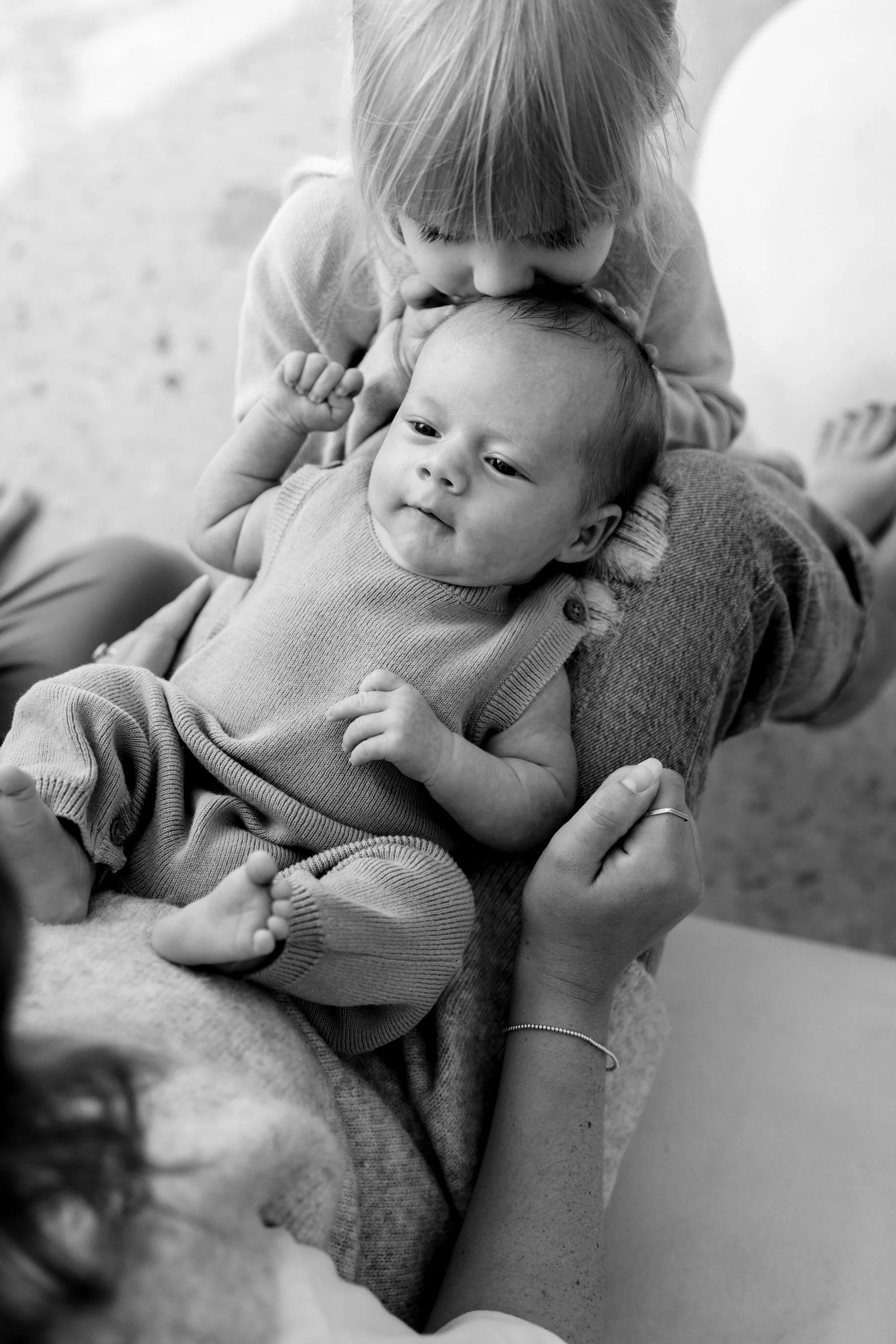 newborn session in natural light setting with baby sister giving baby a kiss, intimate connected photography