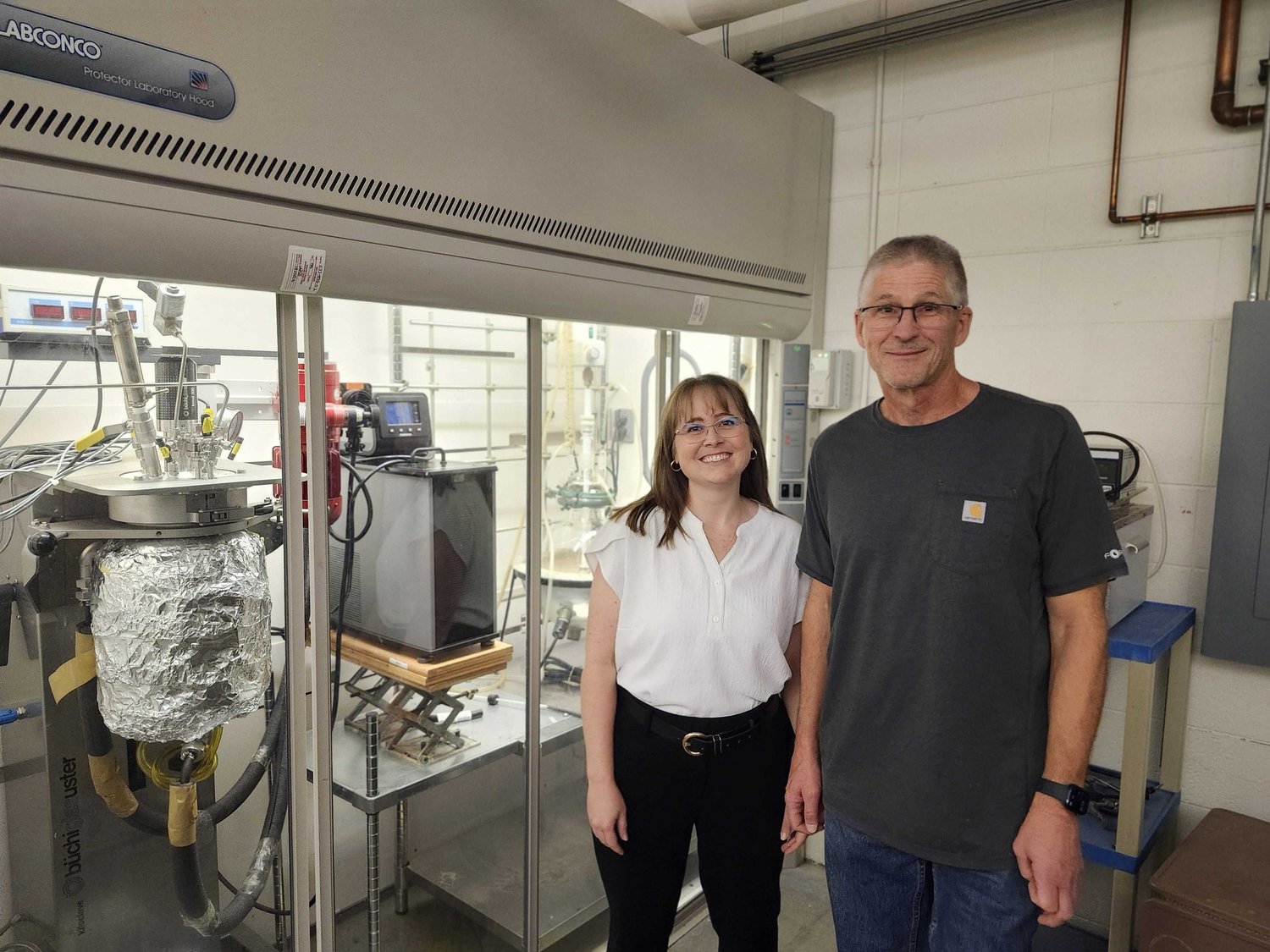 A founder and researcher in front of a laboratory fume hood