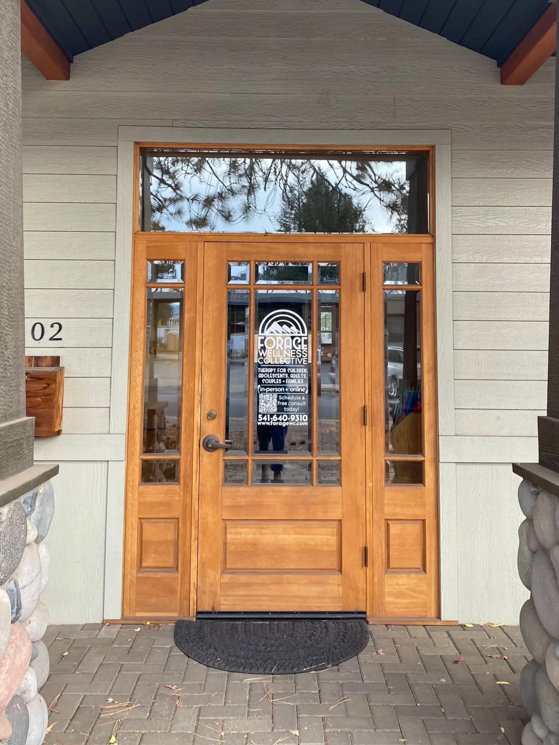 Wooden building exterior with windows and glass doors, greenery above