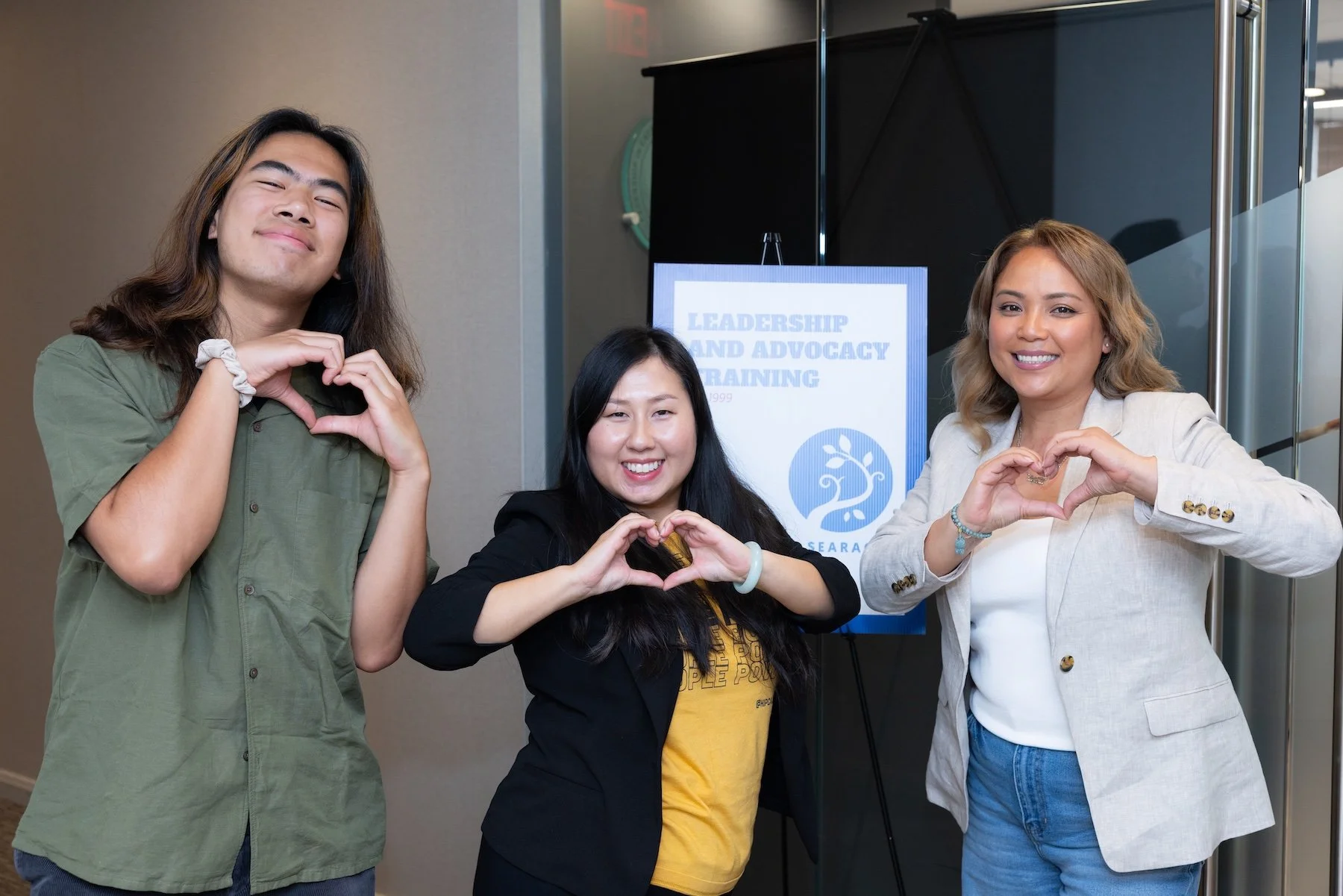 Three individuals pose using their hands to make heart signs