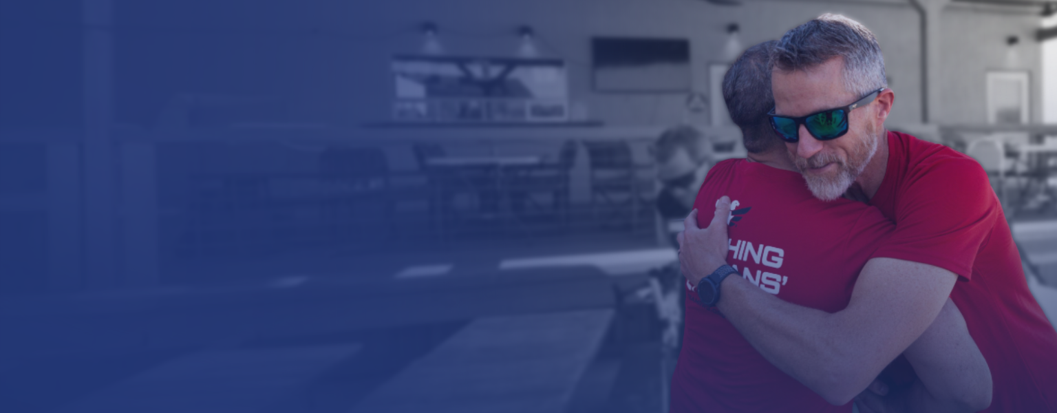 Two men embracing  each other with a hug in a cafe with a modern industrial design.