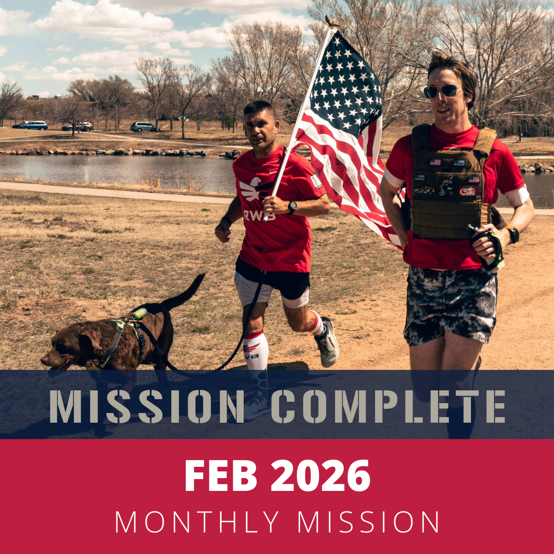 Two men jogging outdoors along a trail near a lake, one holding an American flag, with leafless trees and parked cars in the background, during a sunny day. A dog leads the man on the left. The image is overlaid with text reading 'FEB 2026 MONTHLY MISSION'.