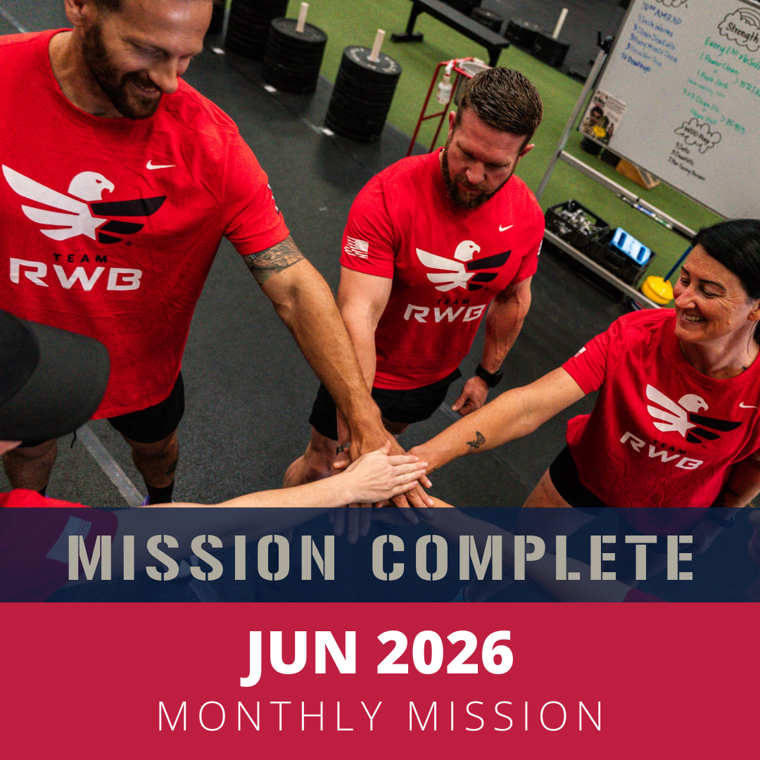 Group of fitness enthusiasts wearing red 'Team RWB' shirts in a gym, putting their hands together in a team huddle, with workout equipment and a whiteboard in the background.