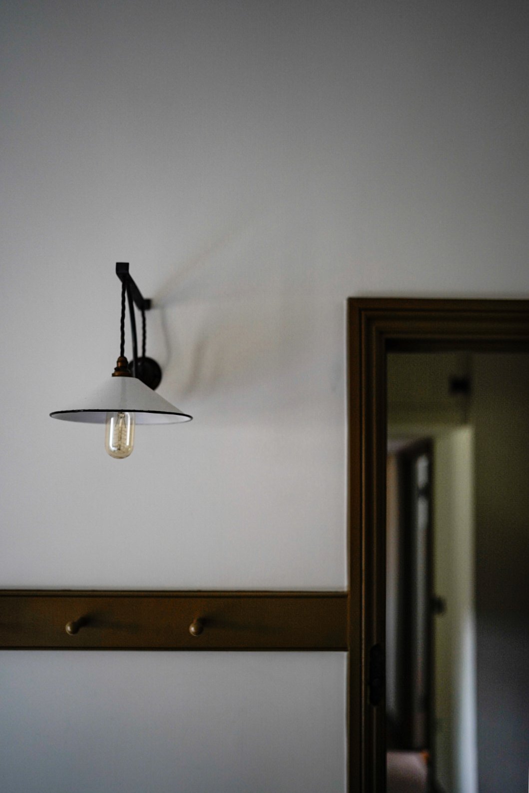 Interior view of a room with a wall-mounted light fixture and a wooden doorframe.