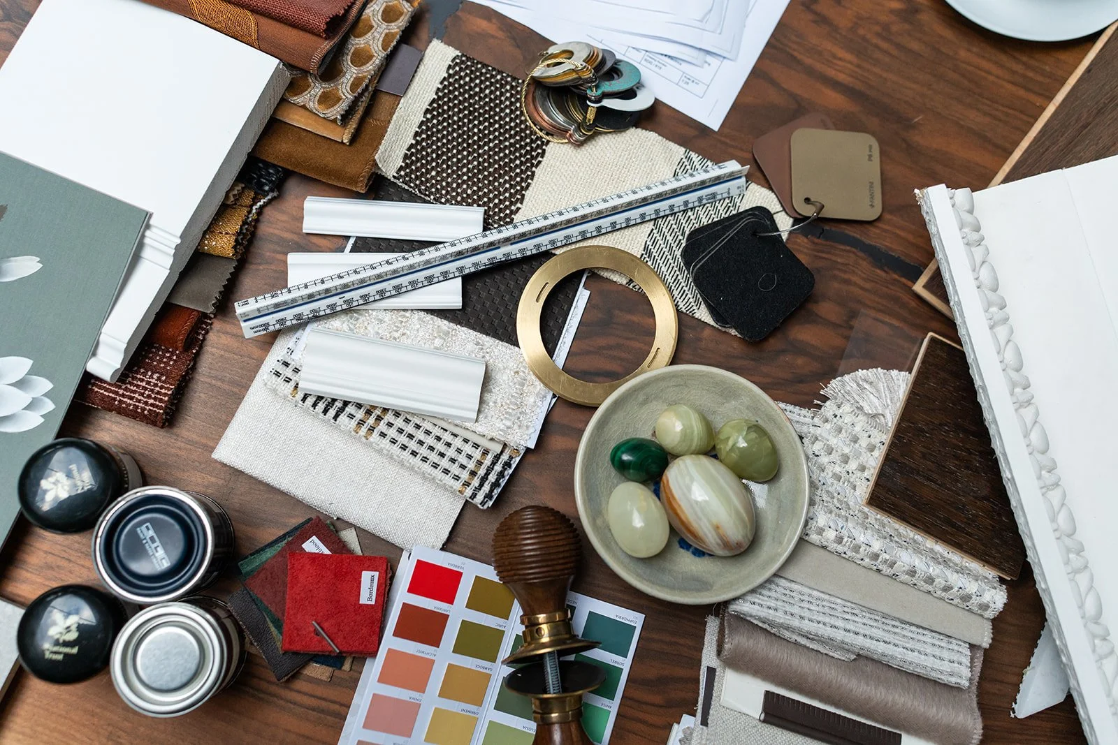 Design palette with fabric swatches, decorative stones, and color samples on a wooden table.