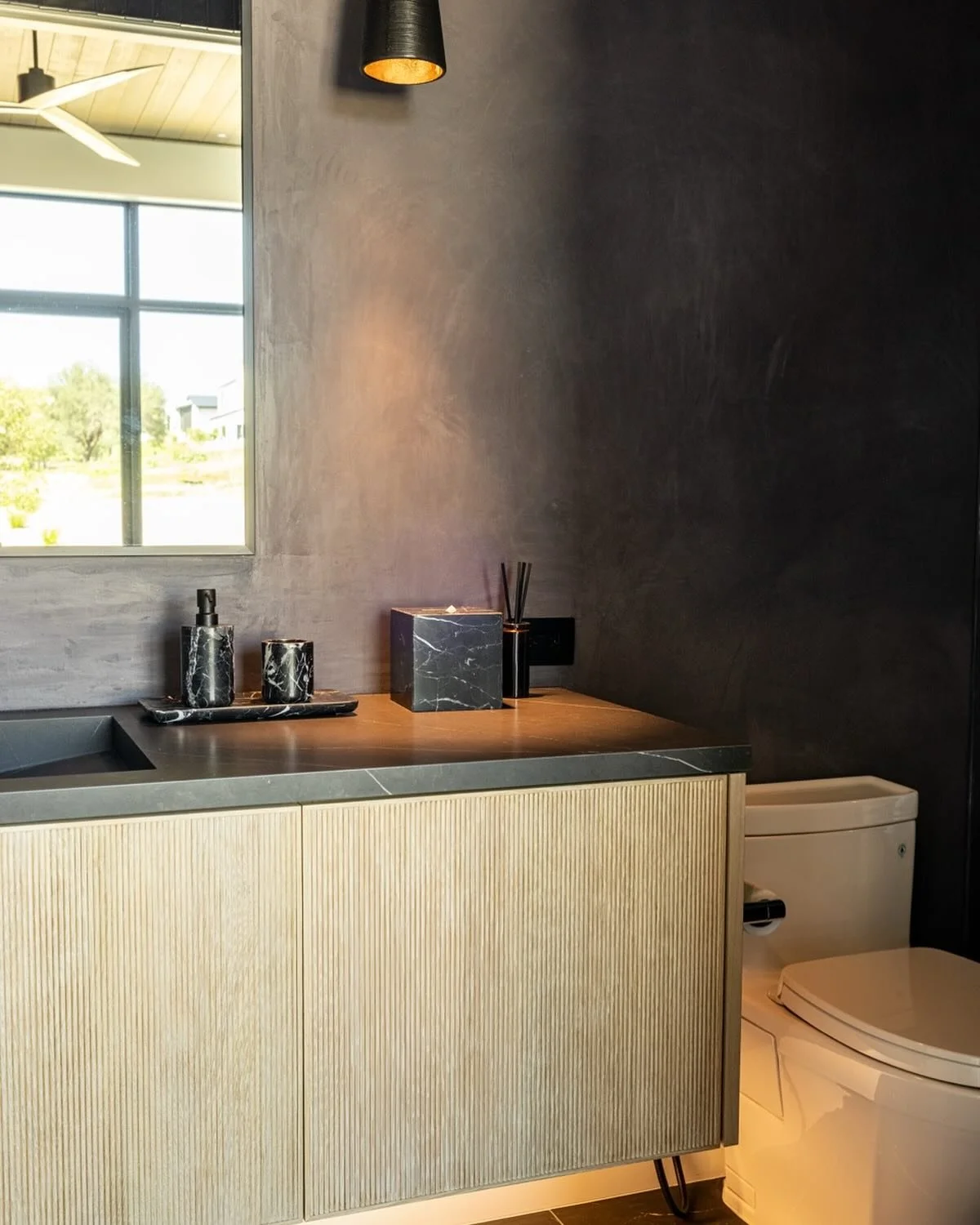 ✨ Spotlight moment! This powder bath is all about the details: smooth plaster walls, bold black countertops, and a custom vanity that steals the show. We created an asymmetrical balance with the mirror and pendant light&mdash;simple, striking, and oh