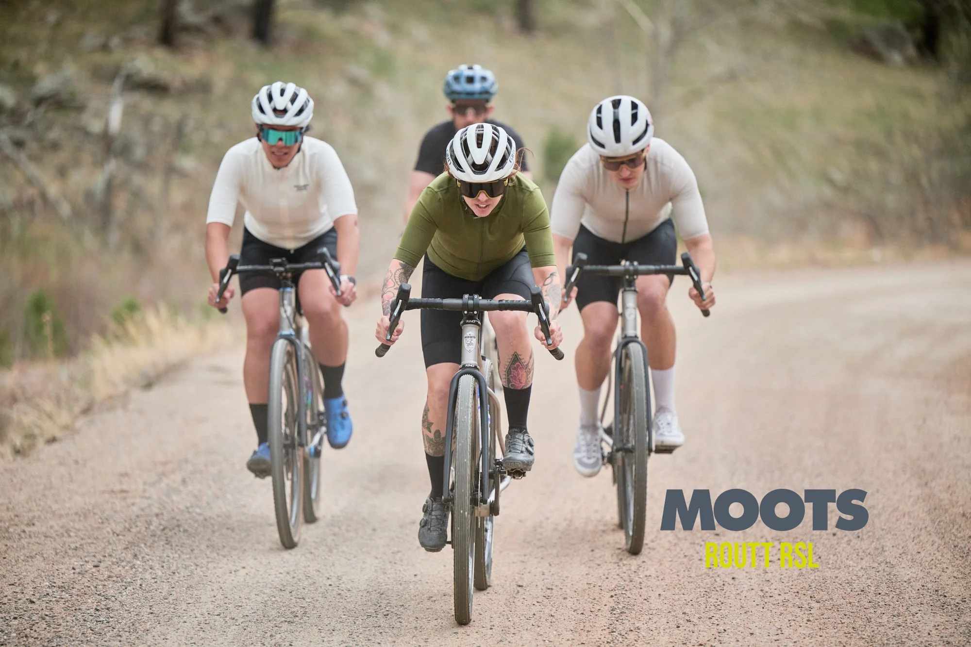 Moots Routt titanium gravel bike on a Colorado dirt road with mountains behind.
