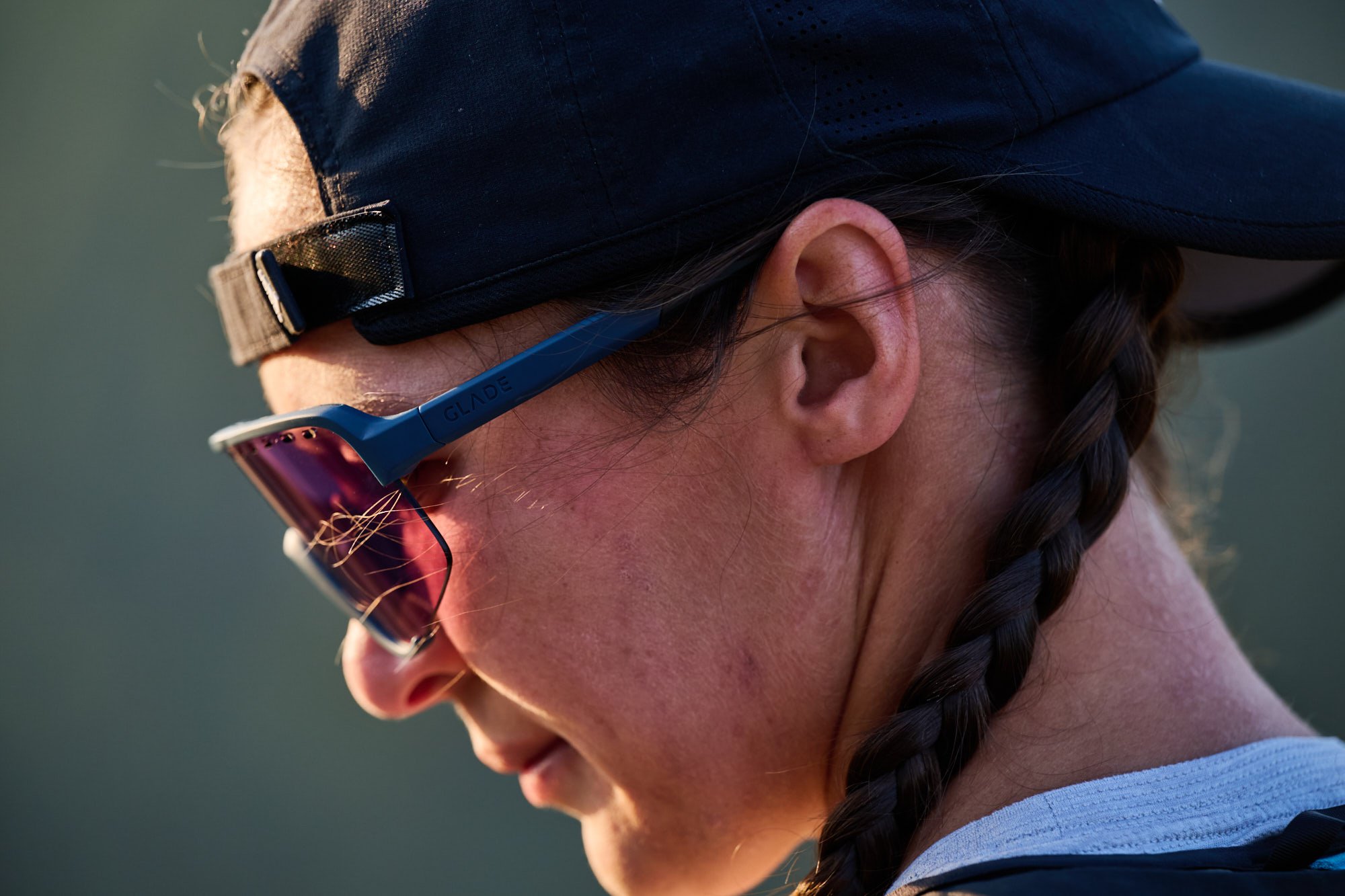 Profile of a trail runner in rose-lens Glade Ramble sunglasses and a run cap, campaign photography for Glade Optics
