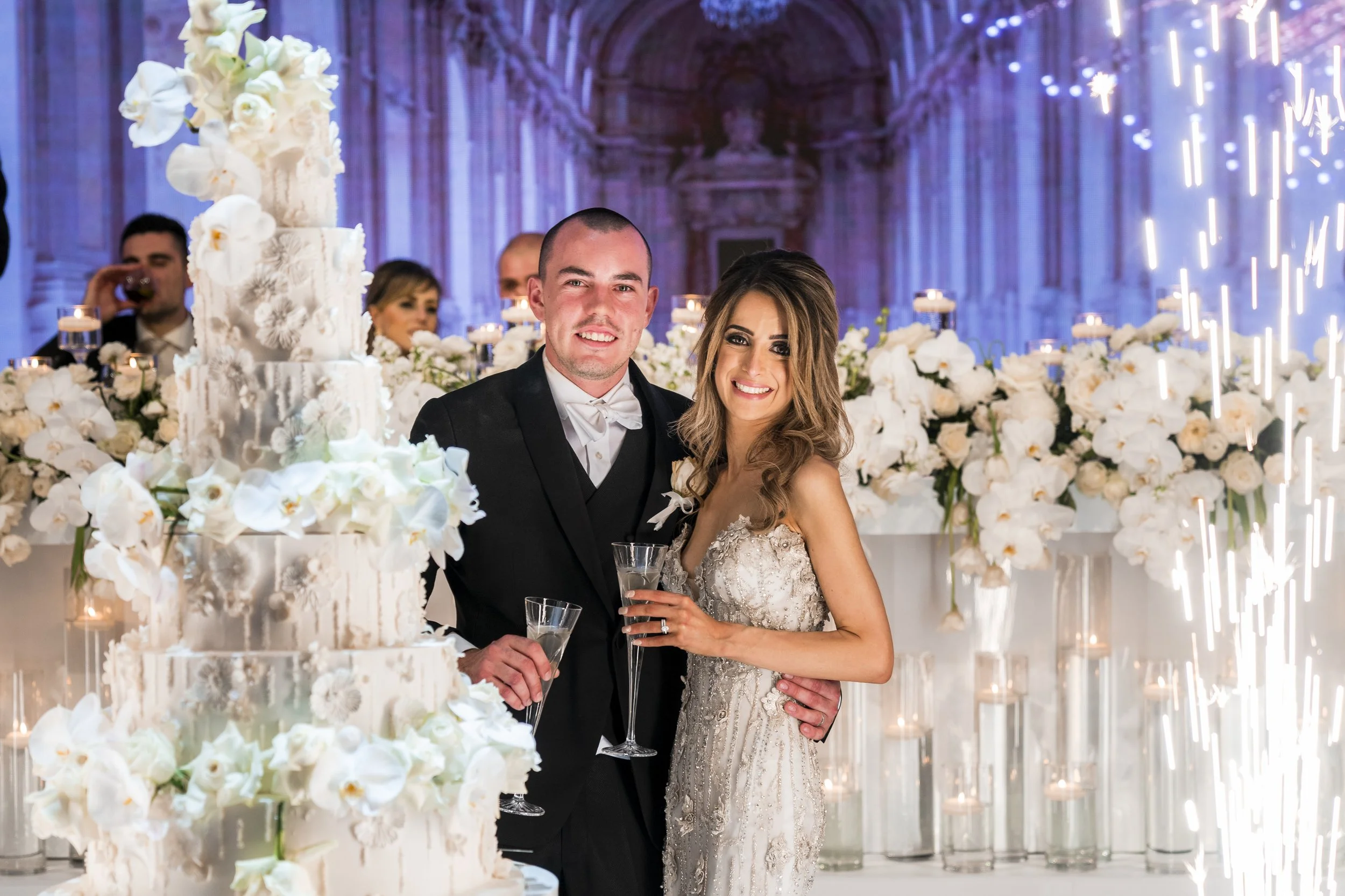 Bride and groom have a tall wedding cake and candlelit backdrop