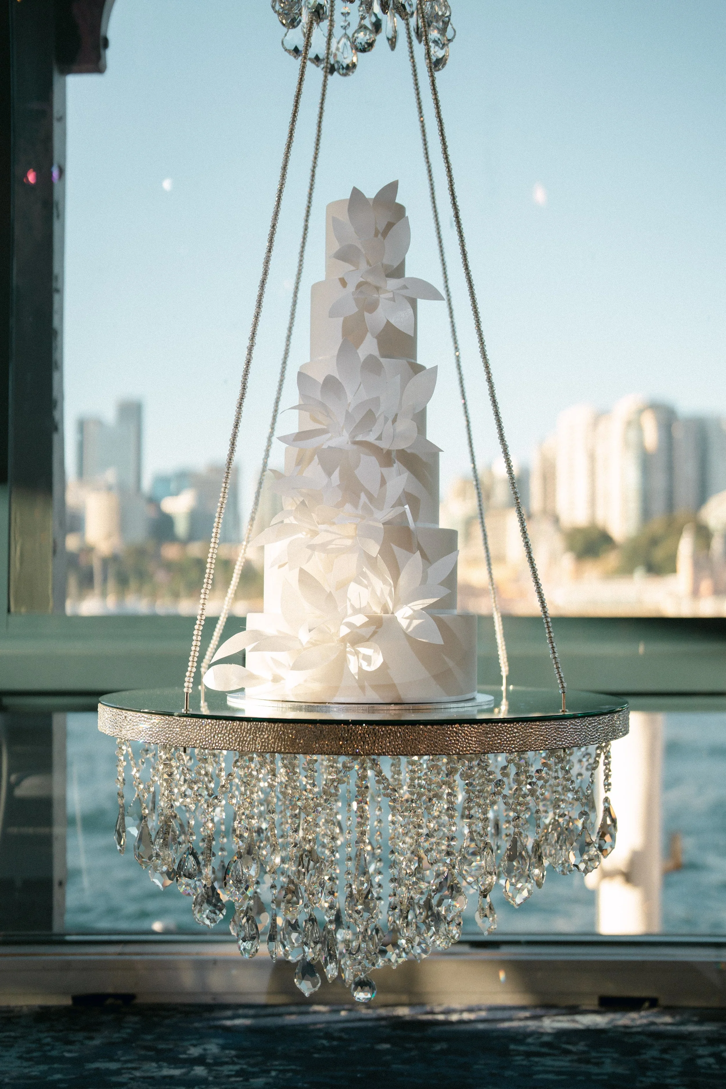 White wedding cake floating on a hanging cake display table.