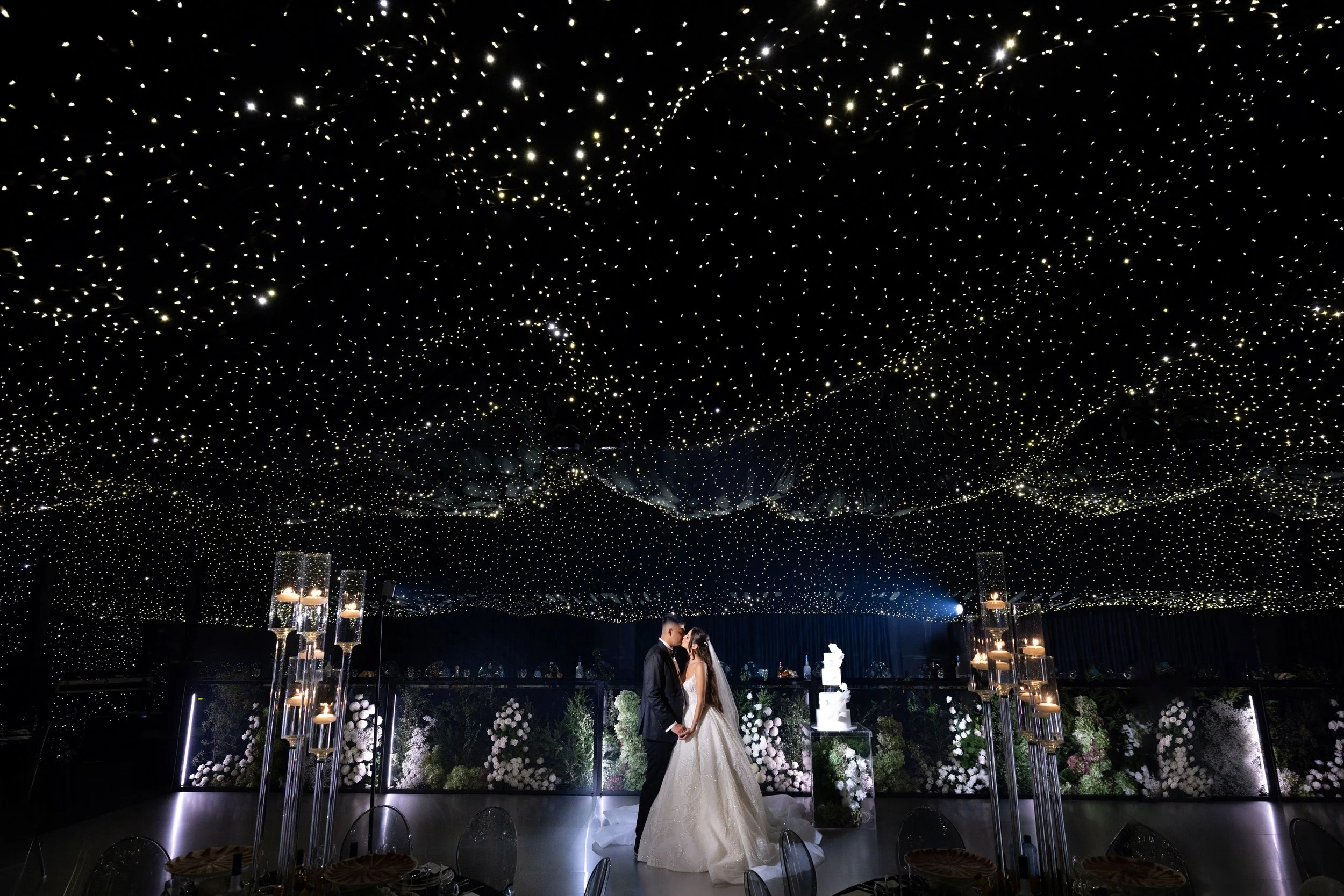 Bride and groom dancing under canopy of fairy lights at wedding recpetion.