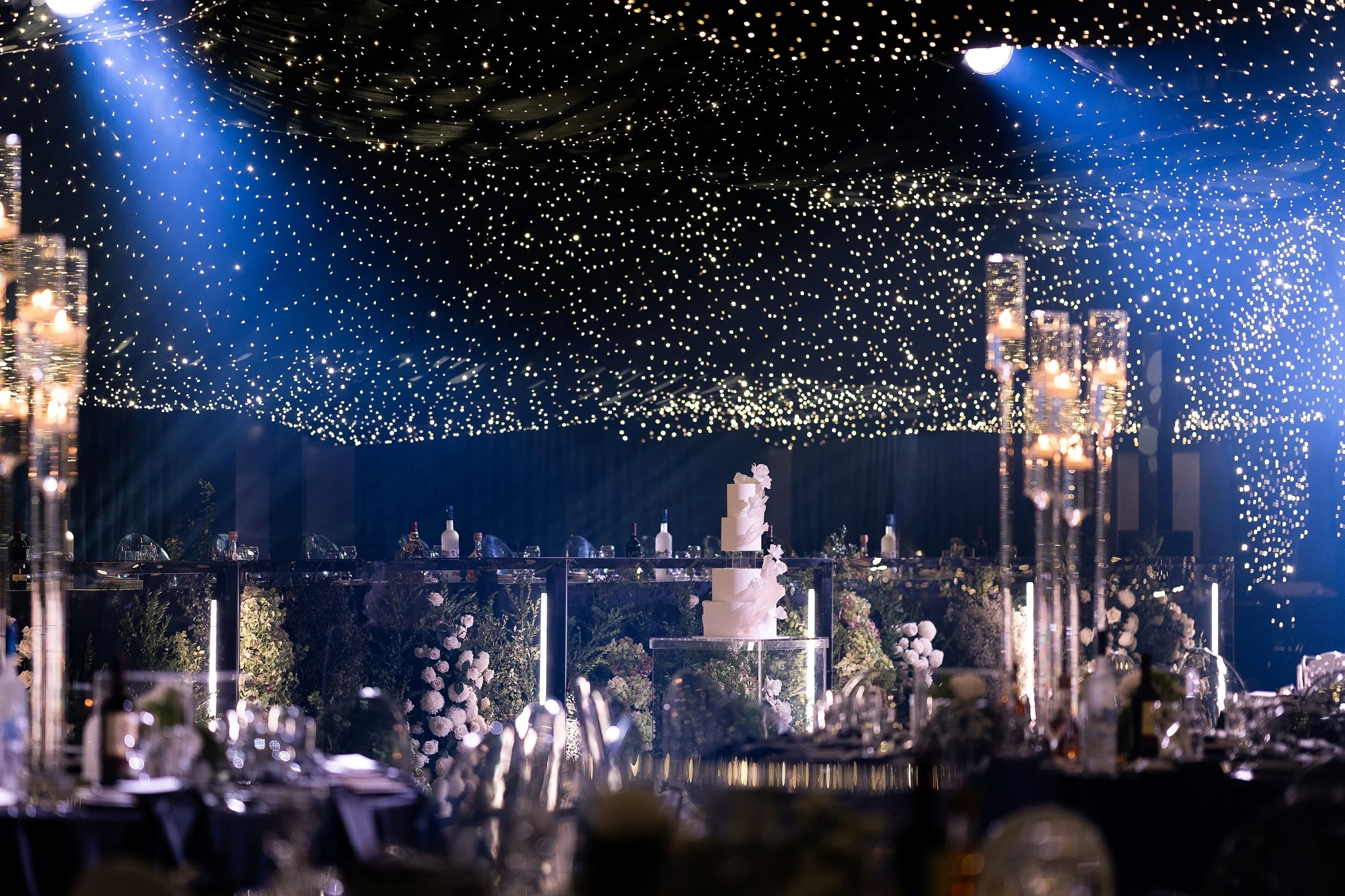 Wedding banquet tables set with white flowers, crystal candelabras and candles.