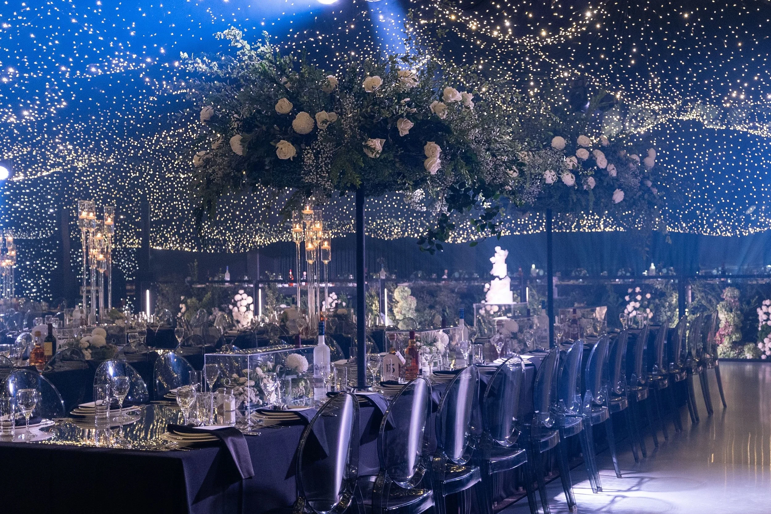 Wedding guests dining under a canopy of fairy lights and decorated tables