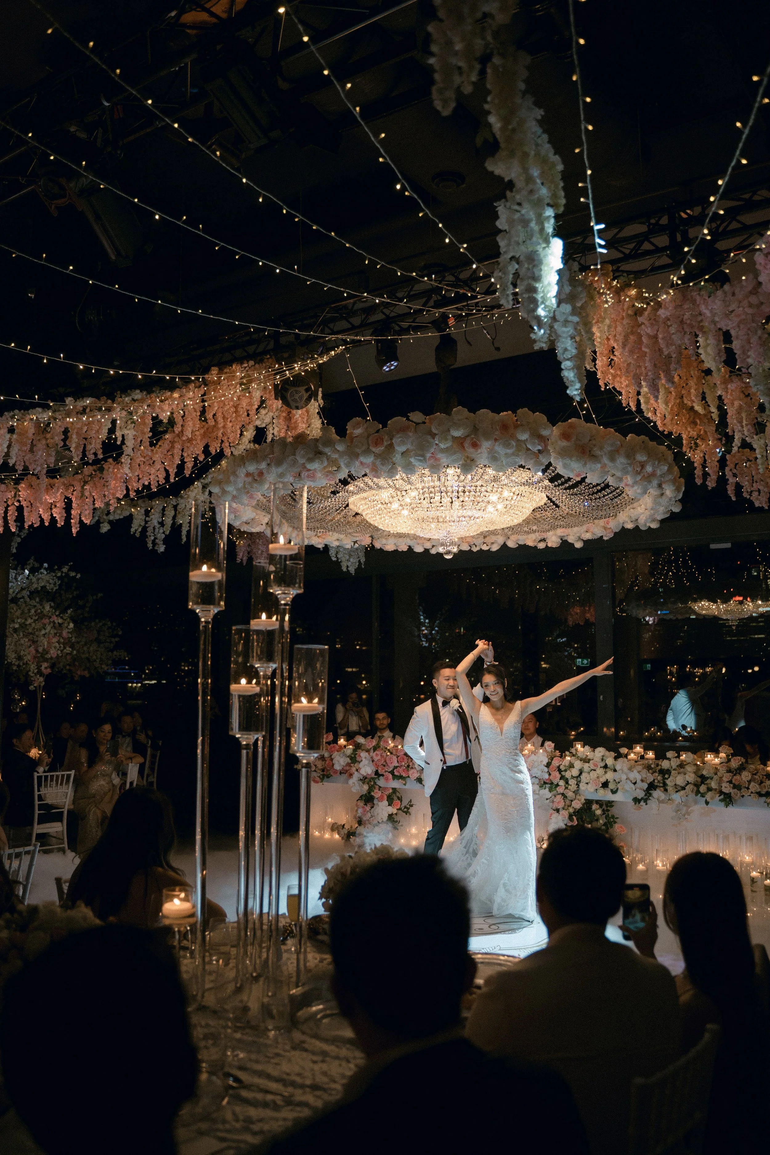 Bride and groom enjoy their first dance under elegant chandelier.
