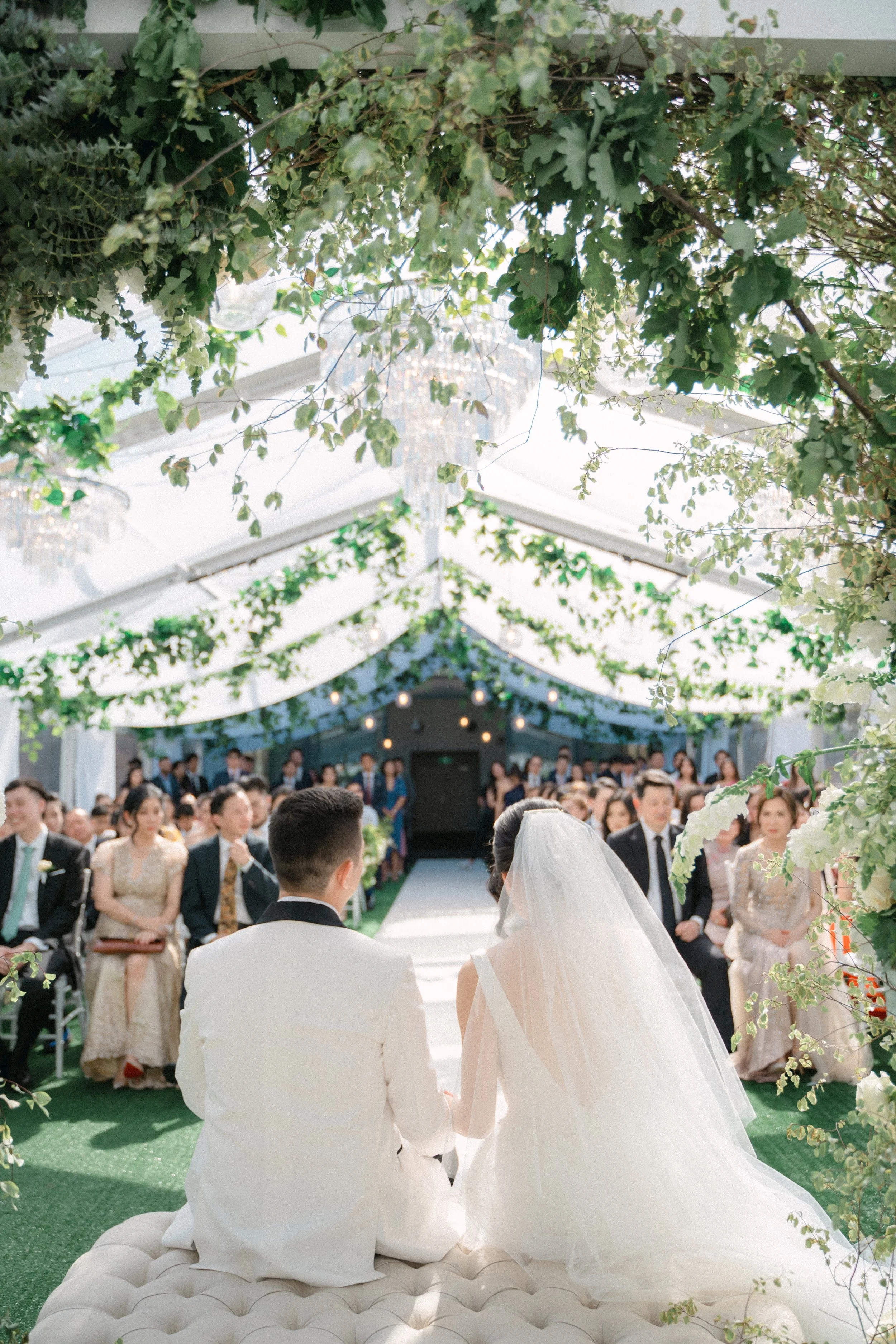 Bride and groom take a moment to enjoy the lush greenery on the ceiling installation