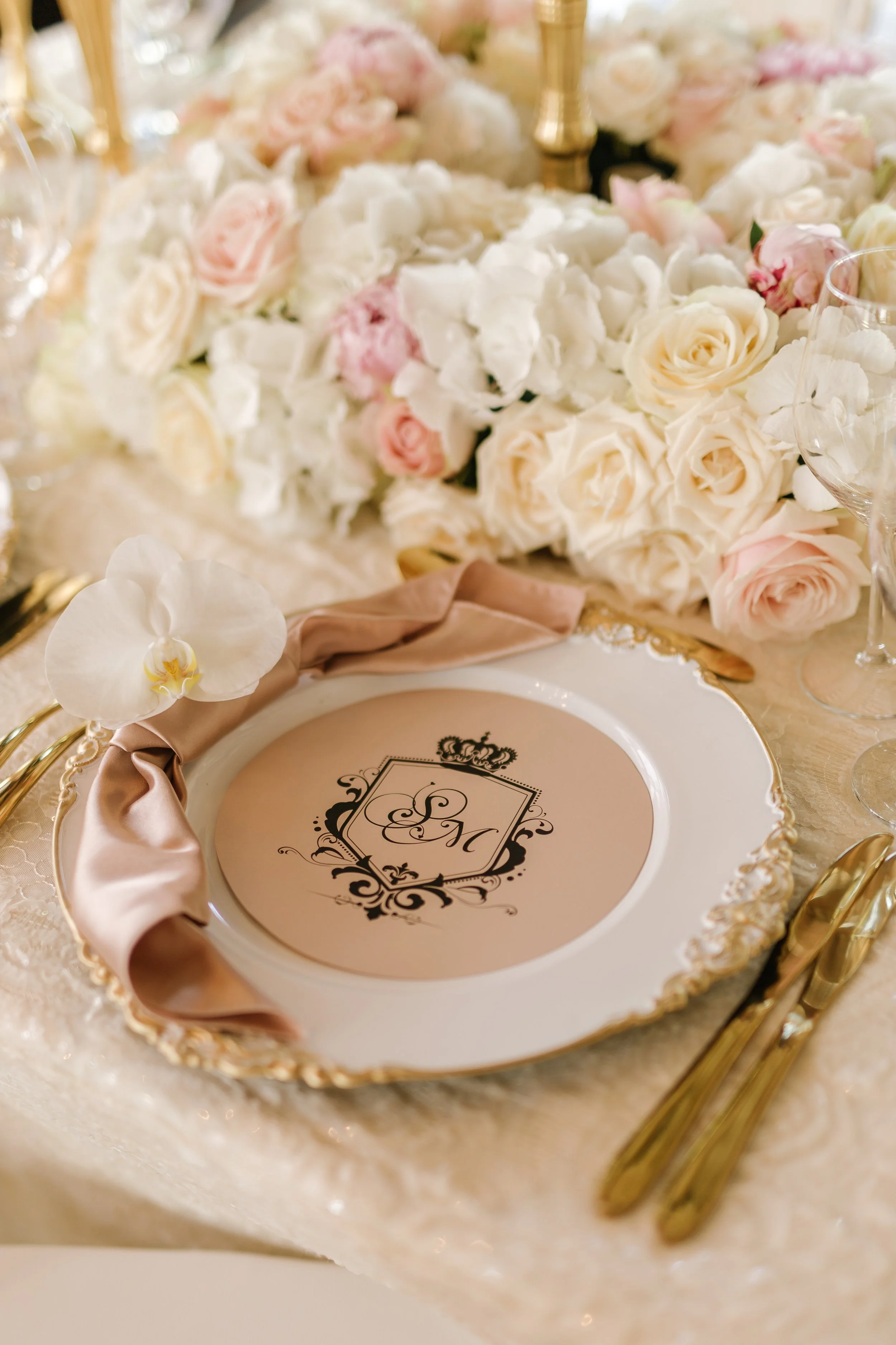 A close up of the guest place setting, with white and gold plates and gold cutlery.