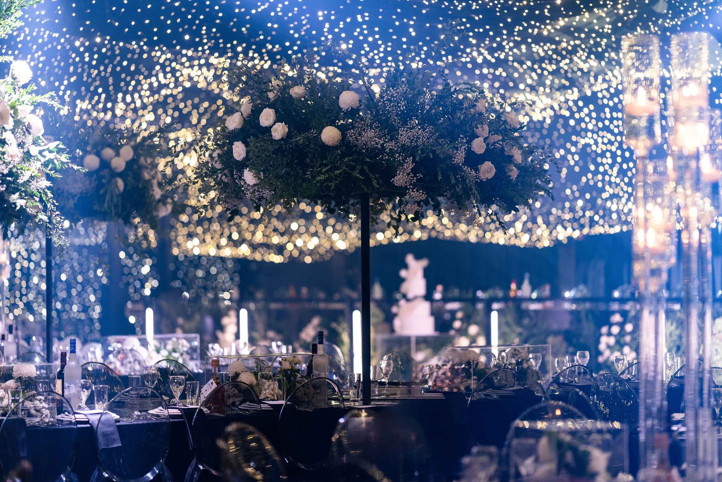 Floral centrepieces on guest tables with illuminated starry backdrop